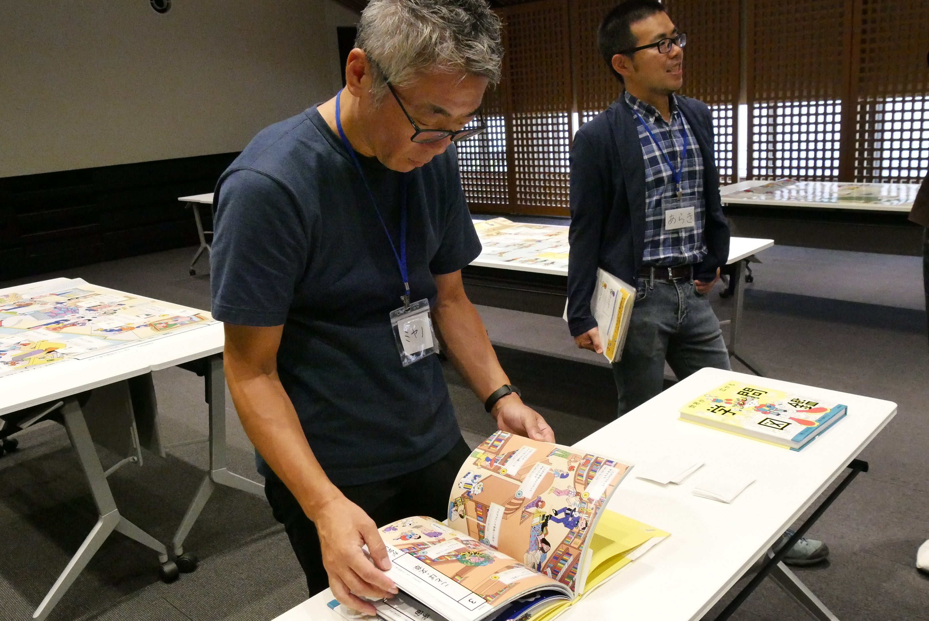 ▲自身が監修した『世界が広がる学問図鑑』を眺める宮野公樹氏（手前）。ワークショップを主催した子どもと大人が学び合う現代の寺子屋「Tera school」を運営するNPO法人寺子屋プロジェクト代表の荒木勇輝氏（奥）。