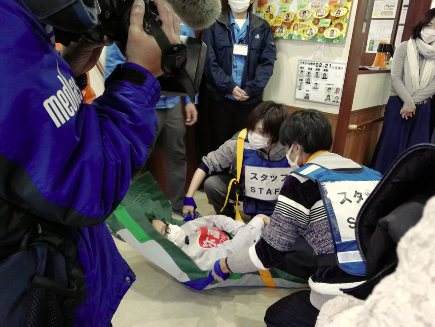 簡易担架でご利用者を2階に上げる訓練の様子（愛の家グループホーム弥富）