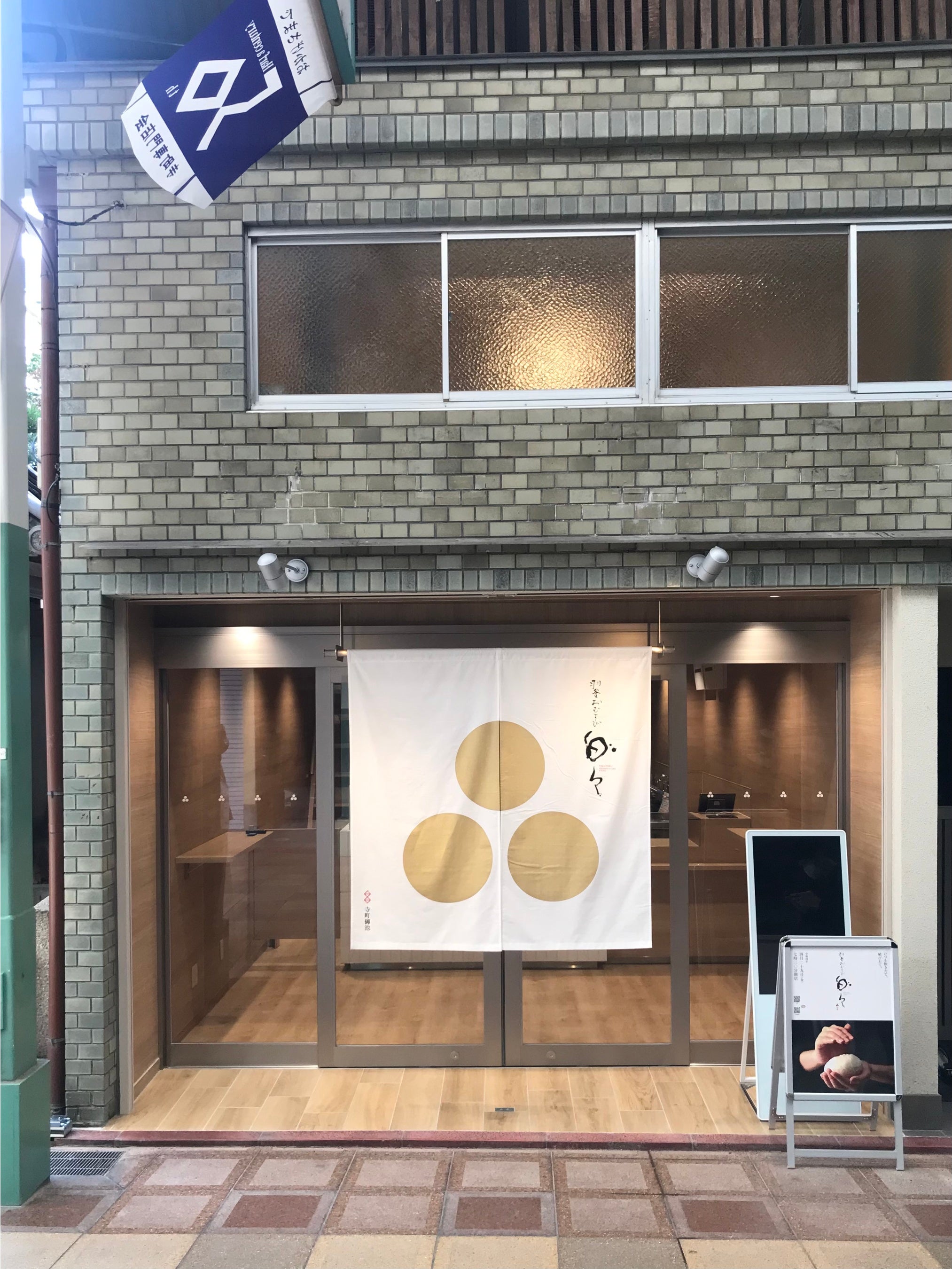 白地に金の俵3つをイメージしたロゴを冠したのれんが目を引く