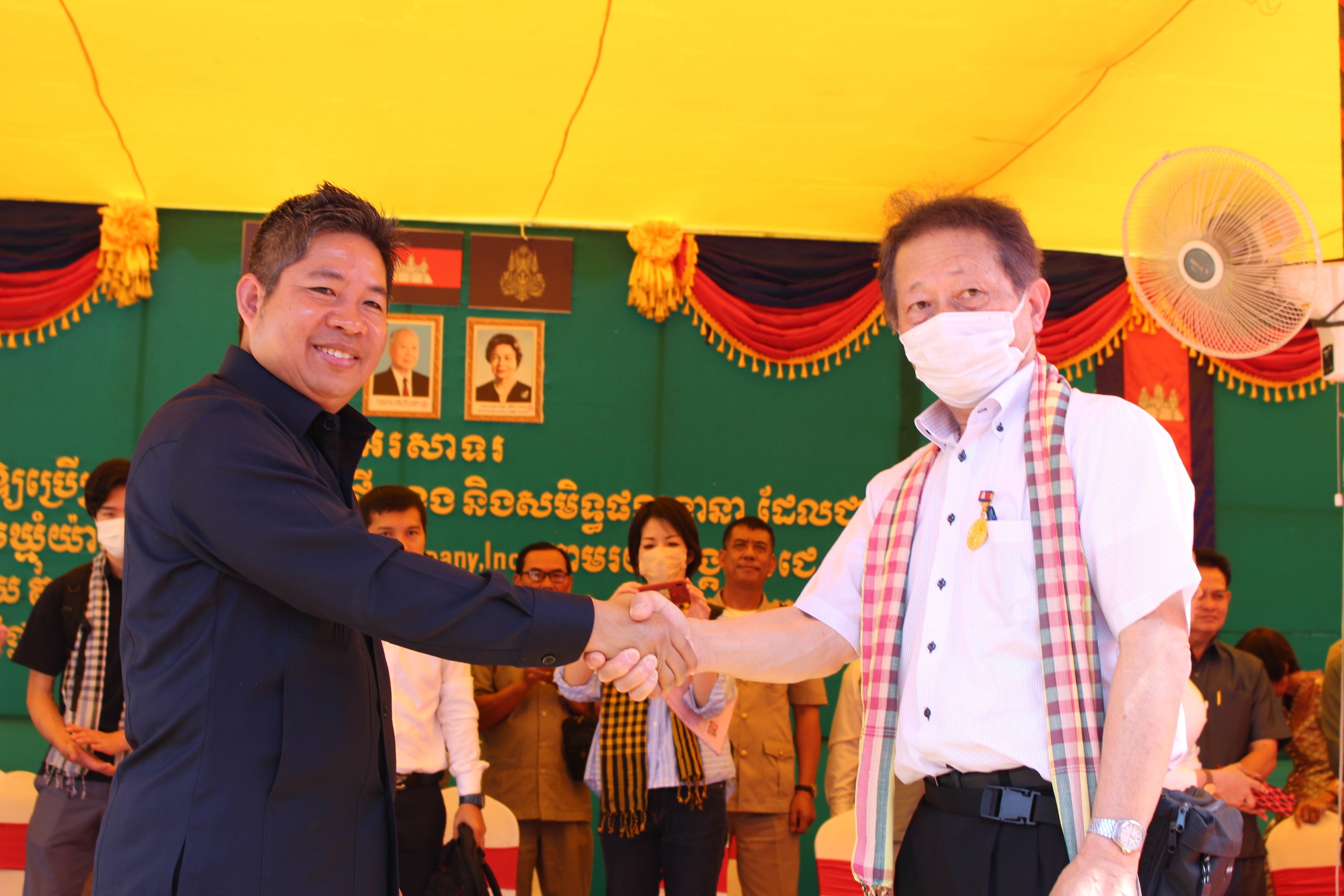 寄贈式で、カンボジア王国司法省秘書官のカエット シカノ氏（左）と握手をする当社取締役・柴田（右）