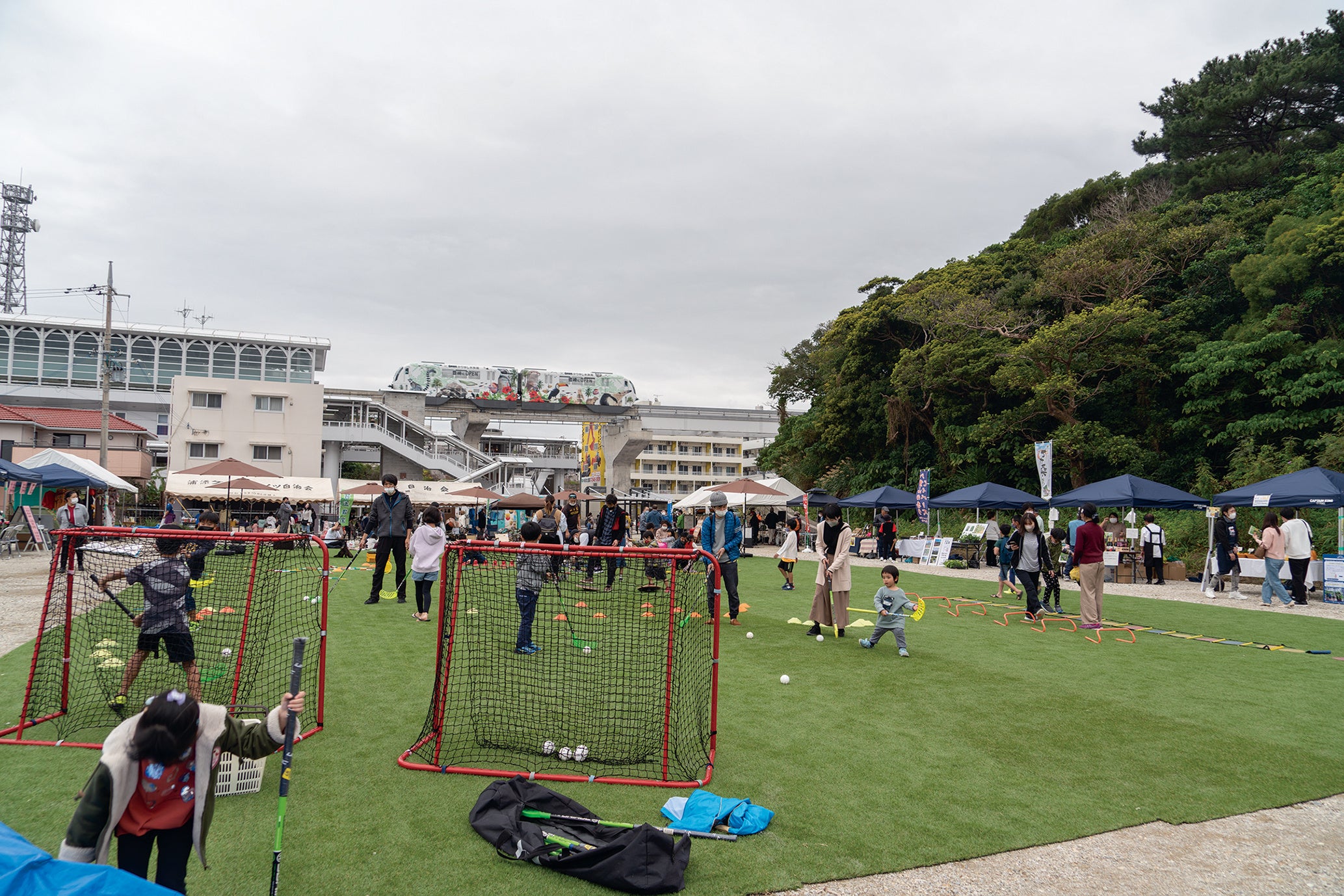２月４日と７日に開催された経塚駅前ヘルシーパークフェスタ。奥に見えるのがモノレールの経塚駅。人工芝広場ではさまざまな運動体験が楽しめた。