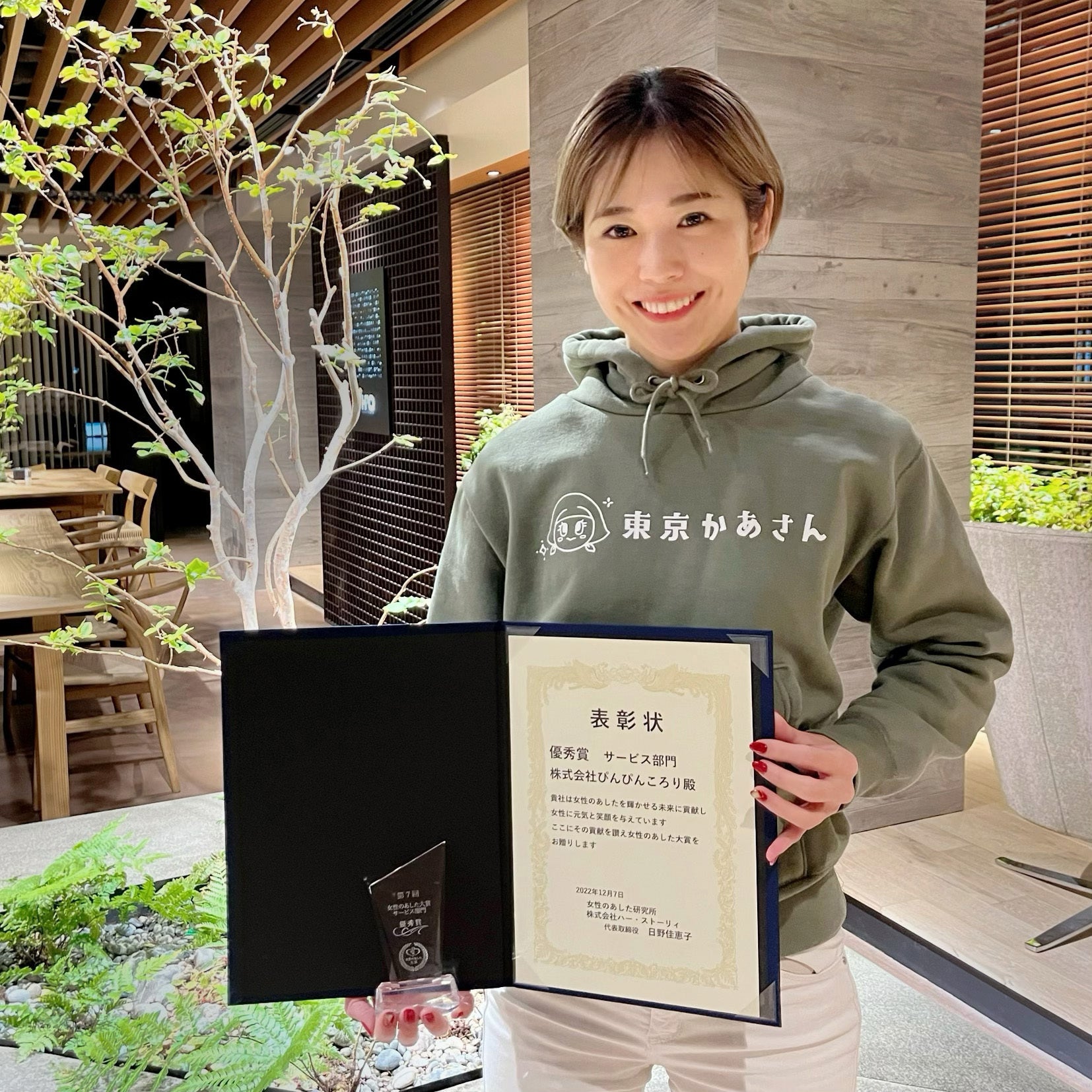 受賞記念の表彰状トロフィーと当社代表 小日向