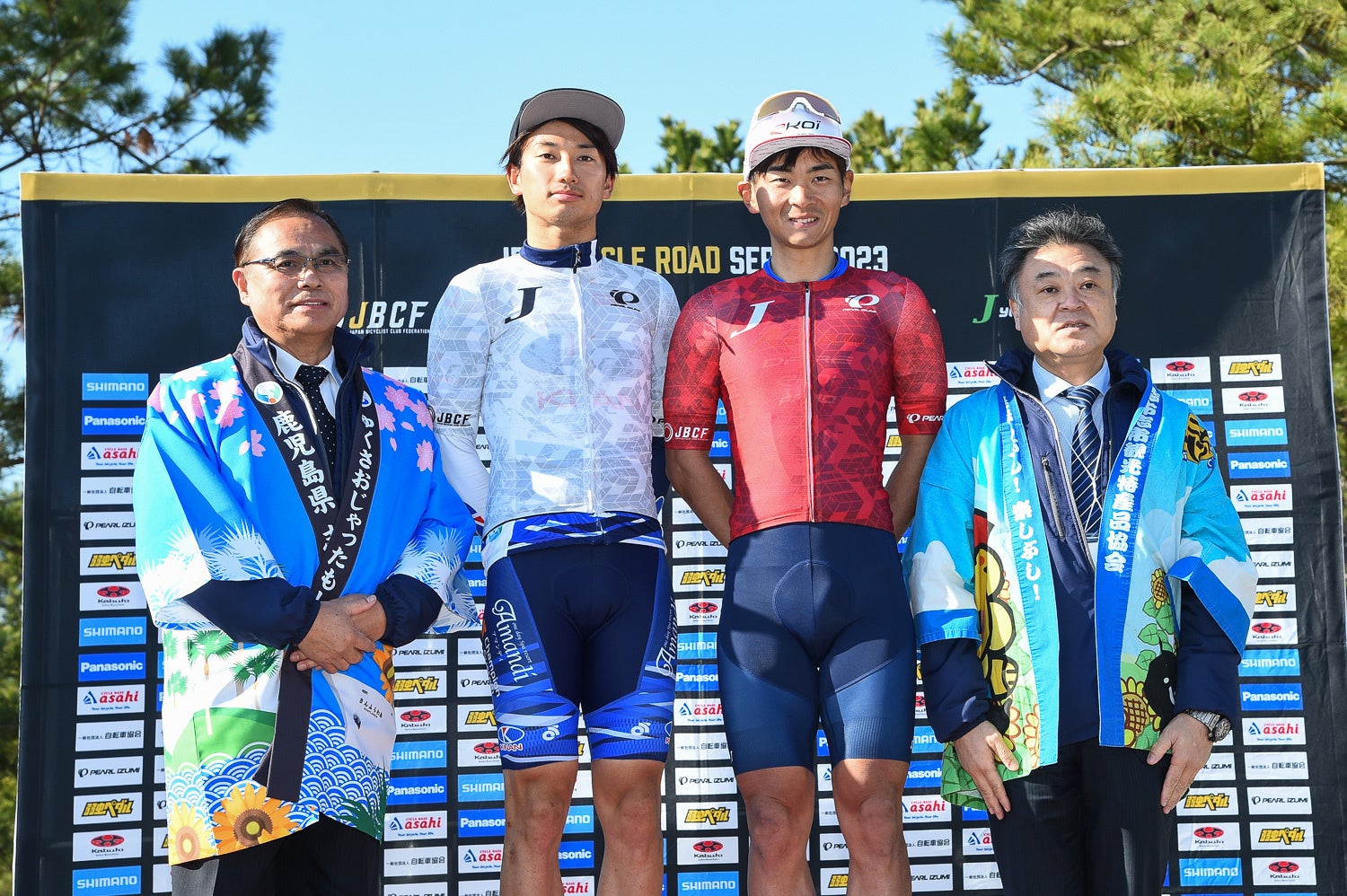 プロリーダージャージの岡本隼（愛三工業レーシングチーム）と、U23ジャージの津田悠義（KINAN Racing Team）　プレゼンターは志布志市の下平晴行市長