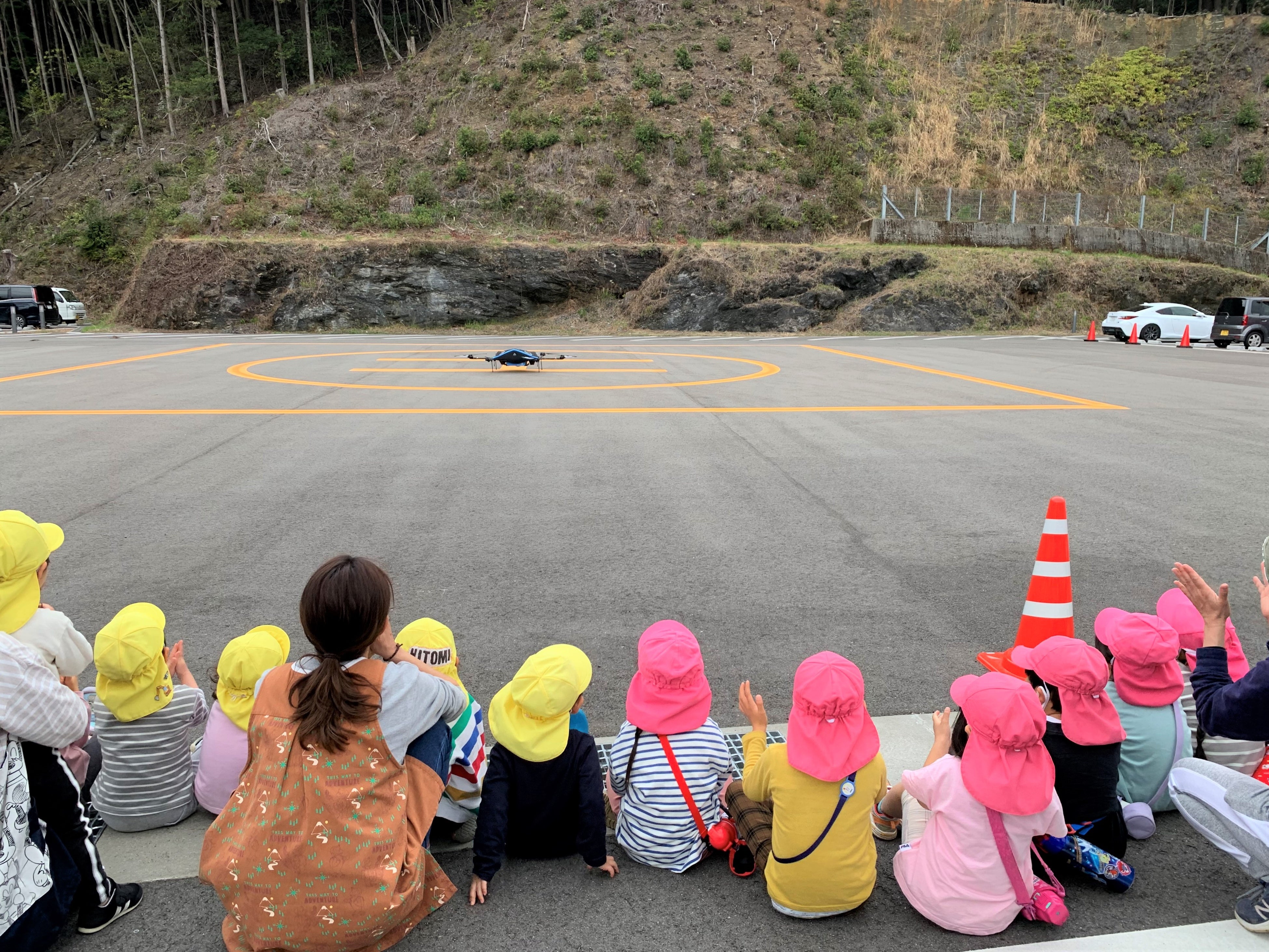 地元シイタケを搭載した物流専用ドローン”AirTruck”の着陸を見守る佐那河内村の保育園児 （佐那河内村役場駐車場）