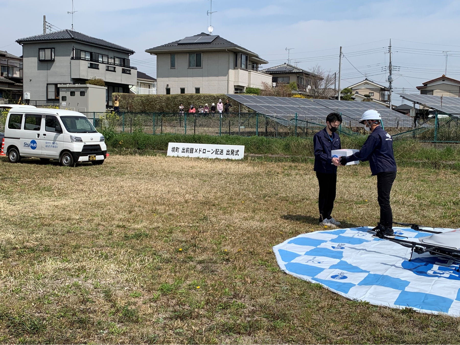 道の駅さかいから軽バンで運ばれたピザをドローンスタッフにリレー