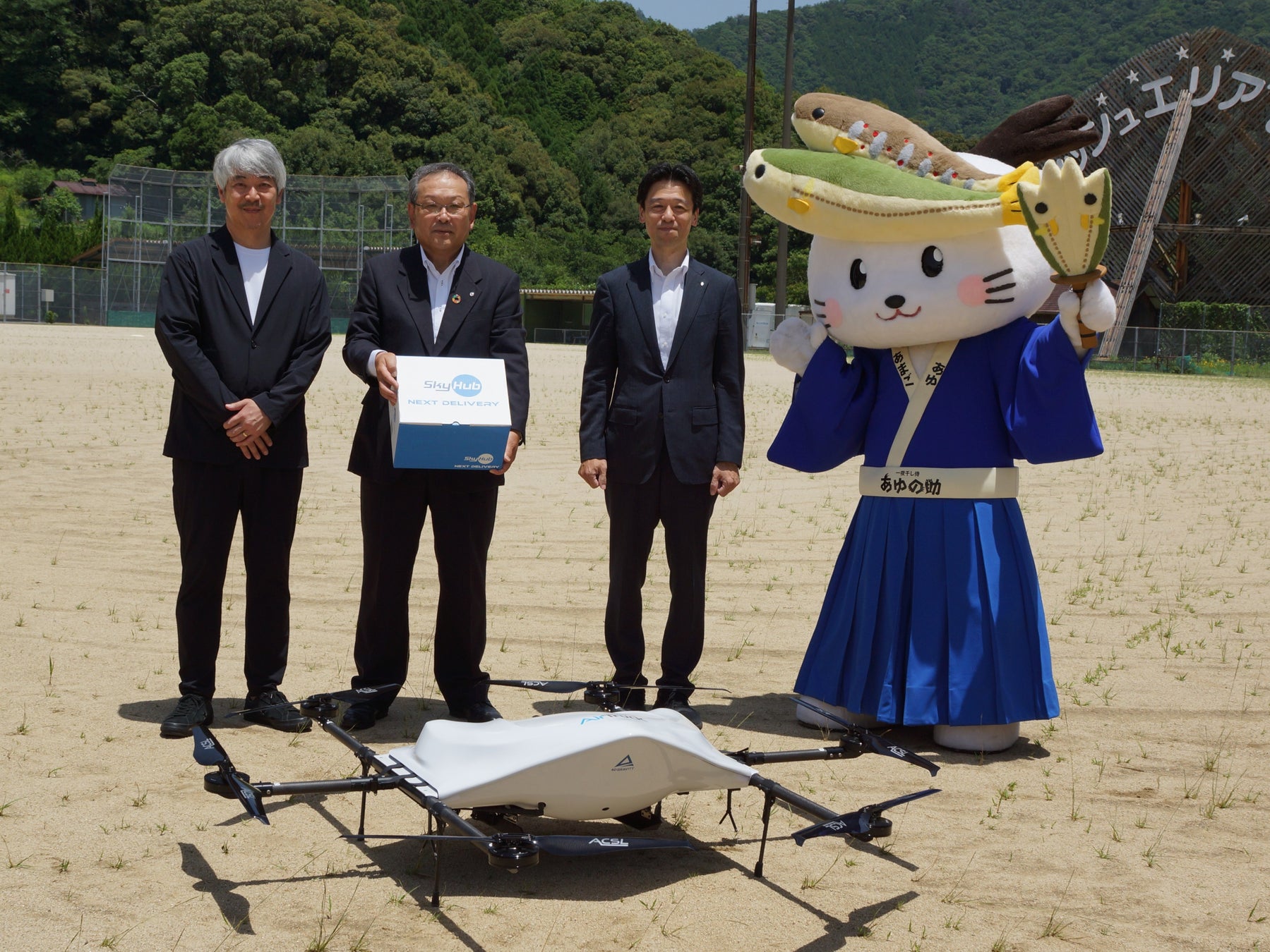 使用したドローンを前に写真向かって左よりエアロネクスト代表取締役CEO・NEXT DELIVERY代表取締役田路圭輔、日高川町長久留米啓史、セイノーHD 執行役員河合秀治
