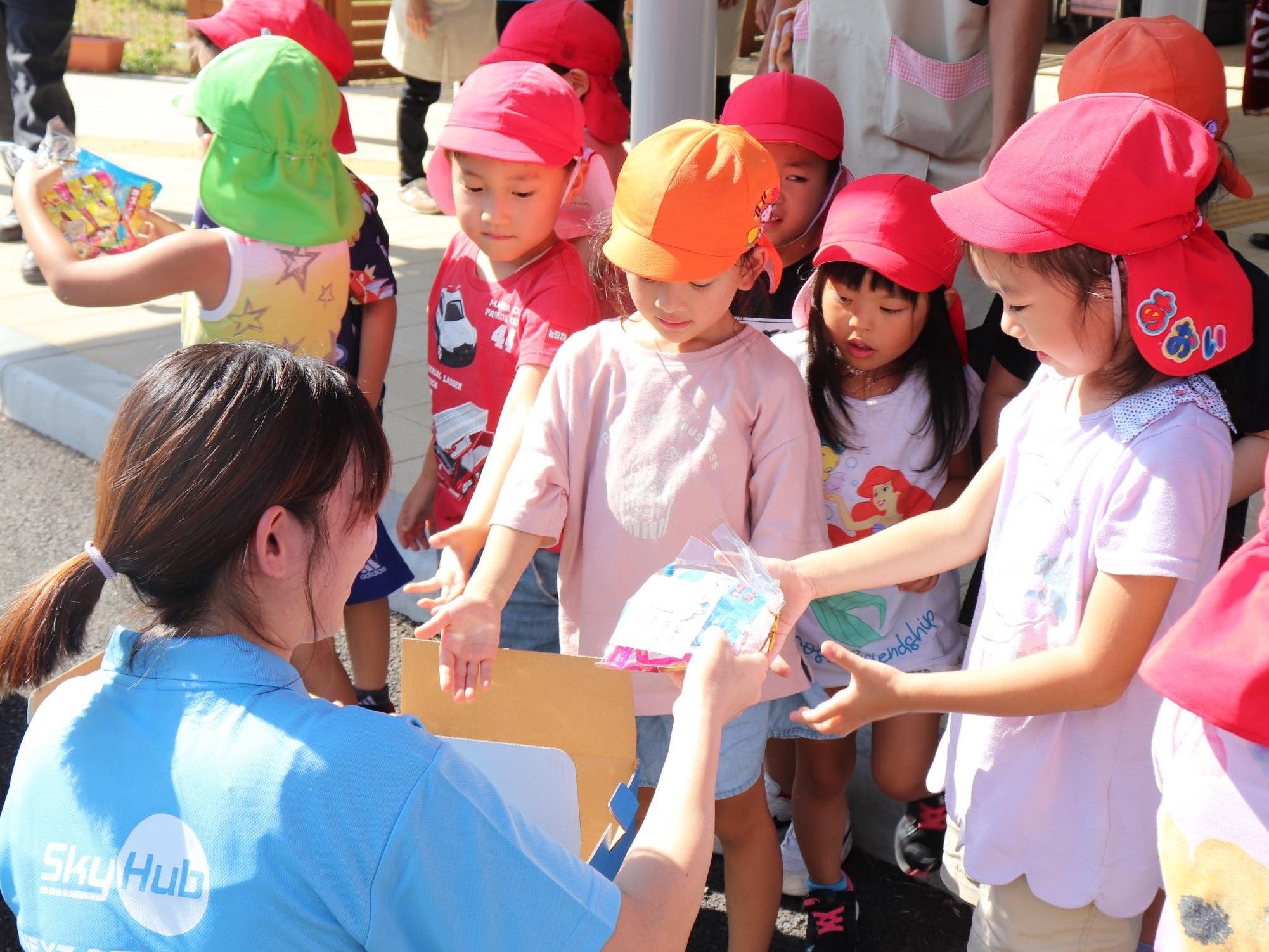 ドローン配送されたお菓子をスタッフから受け取る園児達 （松東こども園）