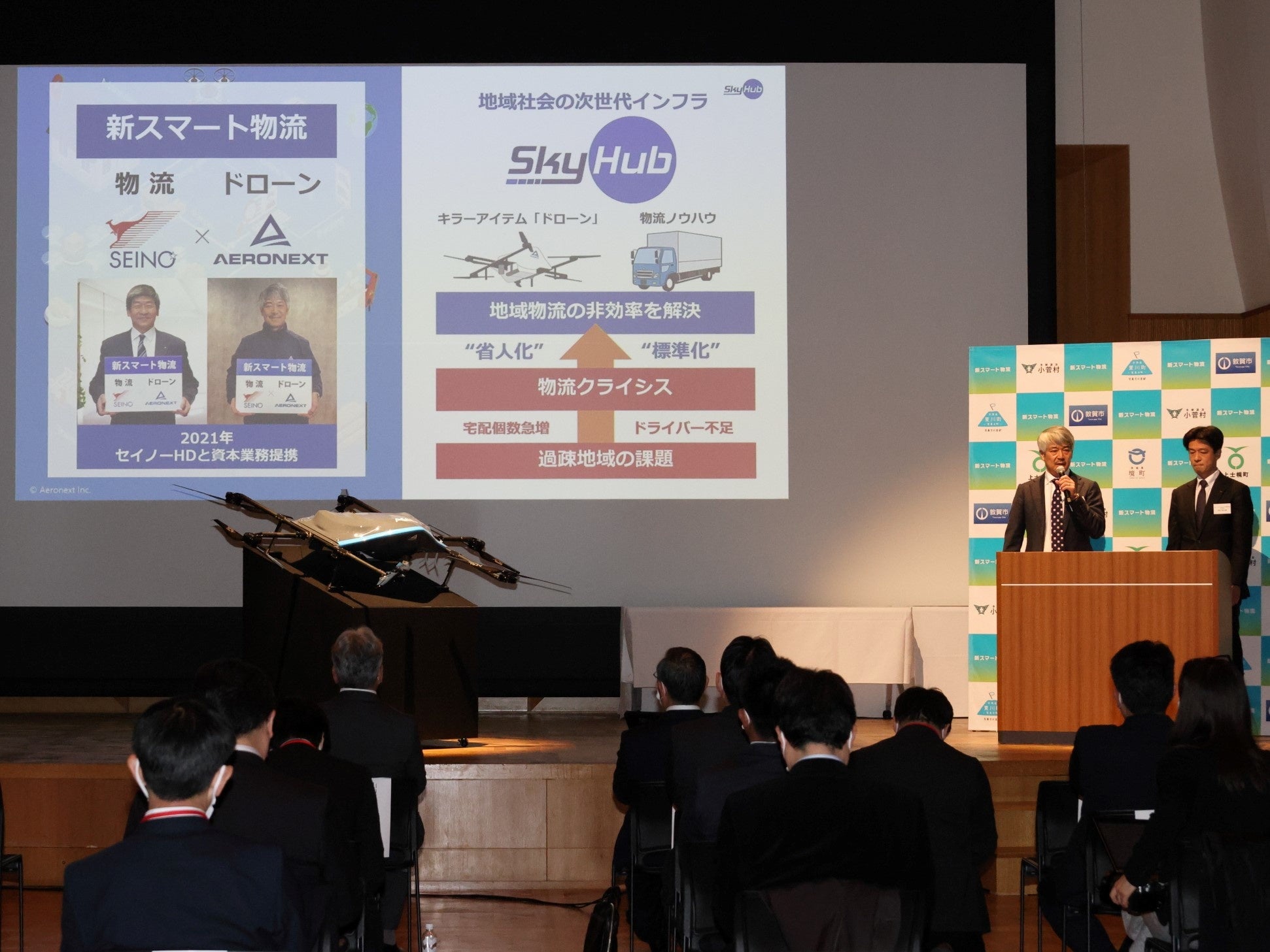 新スマート物流の先進事例としてSkyHub🄬を紹介する写真向かって左よりエアロネクスト代表取締役CEO田路圭輔、セイノーHD執行役員河合秀治