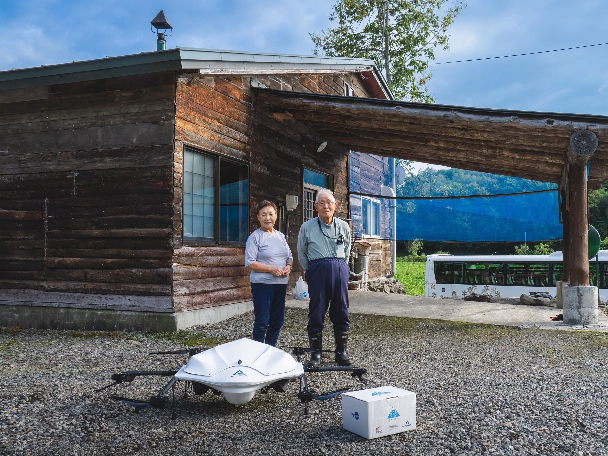 庭先に届いた商品、ドローンと 記念撮影（庄内さんご夫婦）