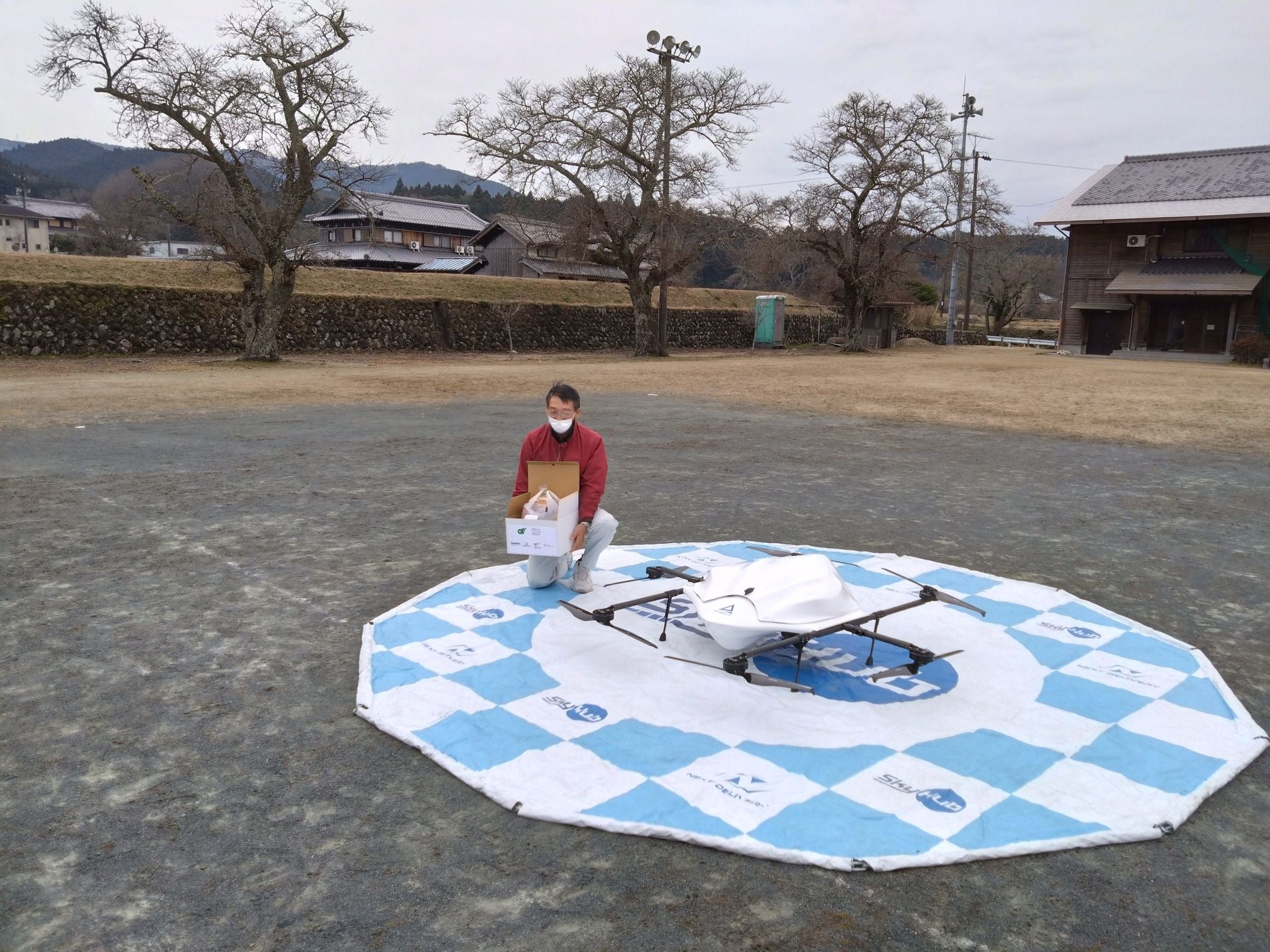 ドローン配送された食料品を 受け取る地域住民モニター （大山田東グラウンドにて）