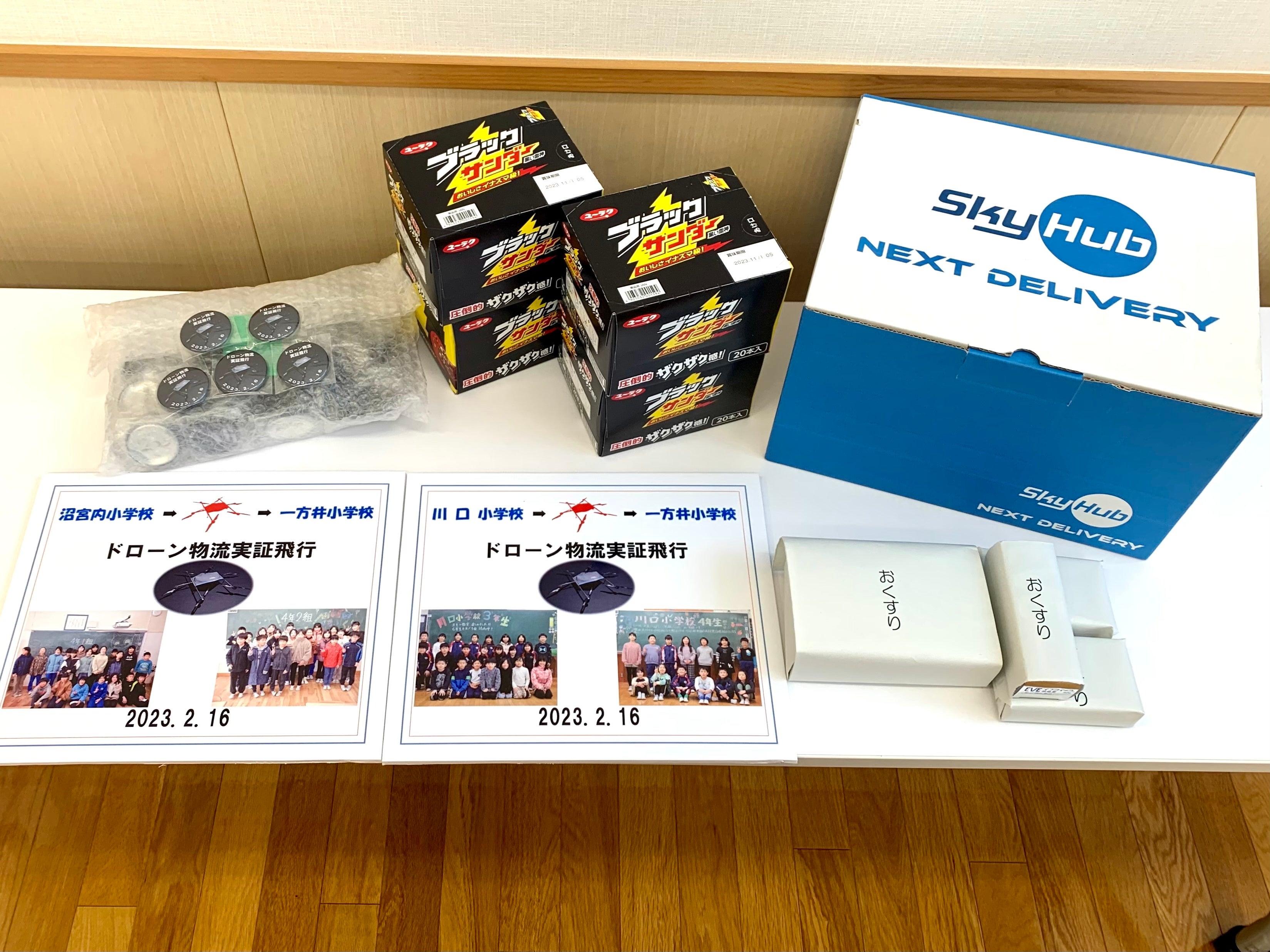 今回ドローン配送された緊急物資（チョコレート）・医薬品を想定した空箱・メッセージボード・記念バッジ