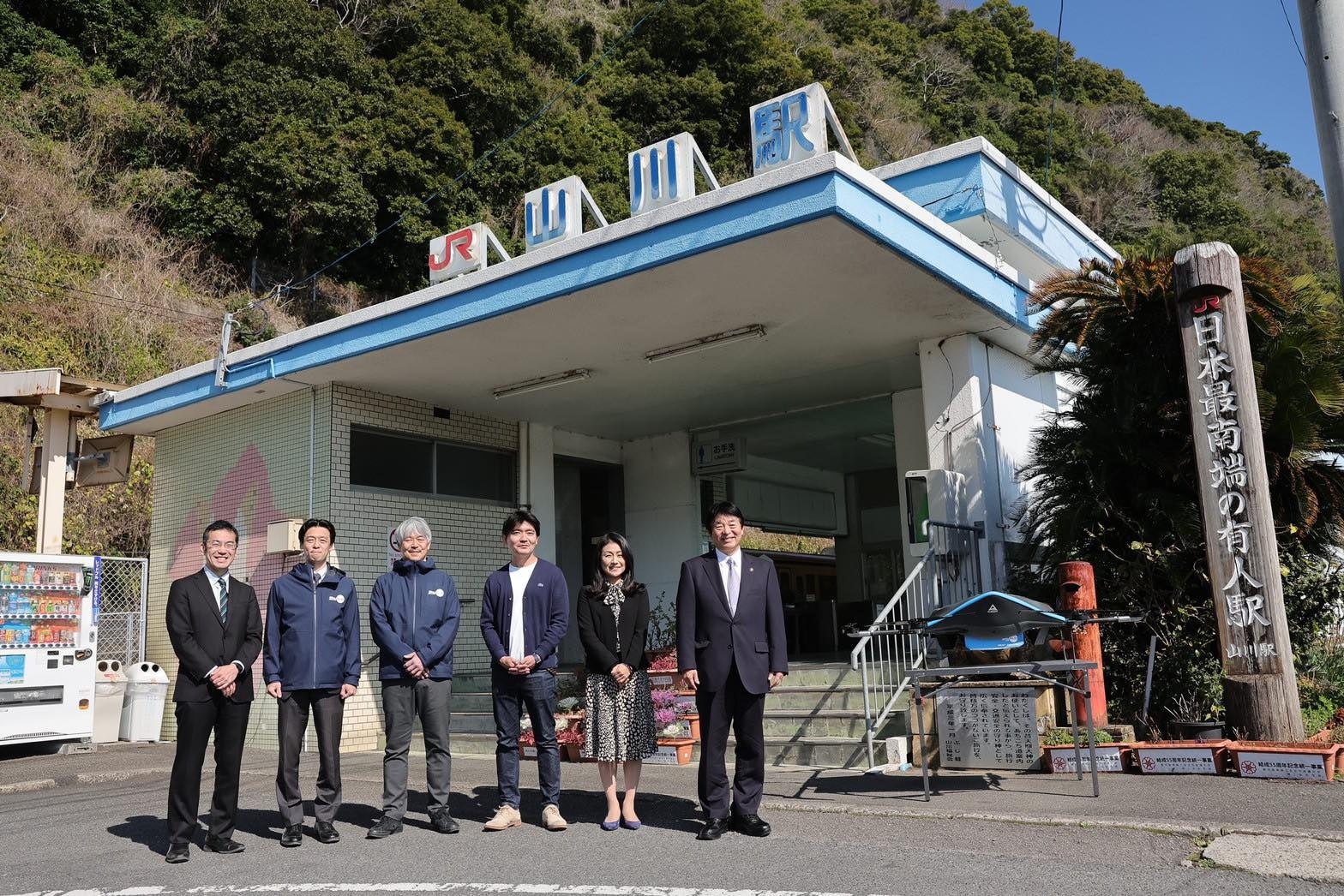 写真右より 指宿市 市長 打越 明司、 JR九州　上席執行役員経営企画部長　赤木由美、 チェンジ鹿児島 中垣雄、 エアロネクスト代表取締役CEO 田路圭輔、 セイノーHD 執行役員　河合秀治、 KDDIスマートドローン代表取締役社長　博野雅文