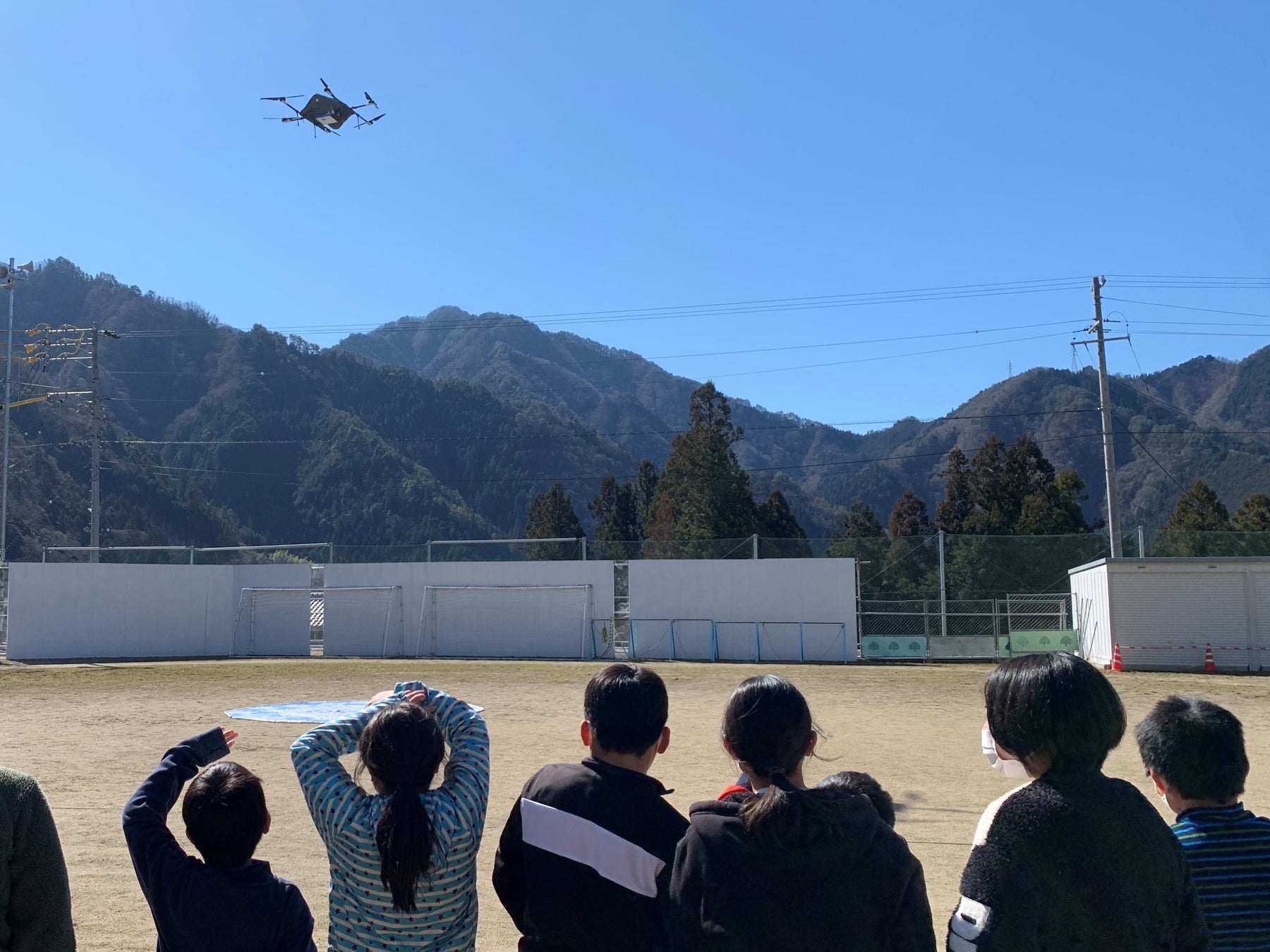 物流専用ドローン”AirTruck”の着陸を見守る天龍村小学校の児童たち (天龍村小学校グラウンド)