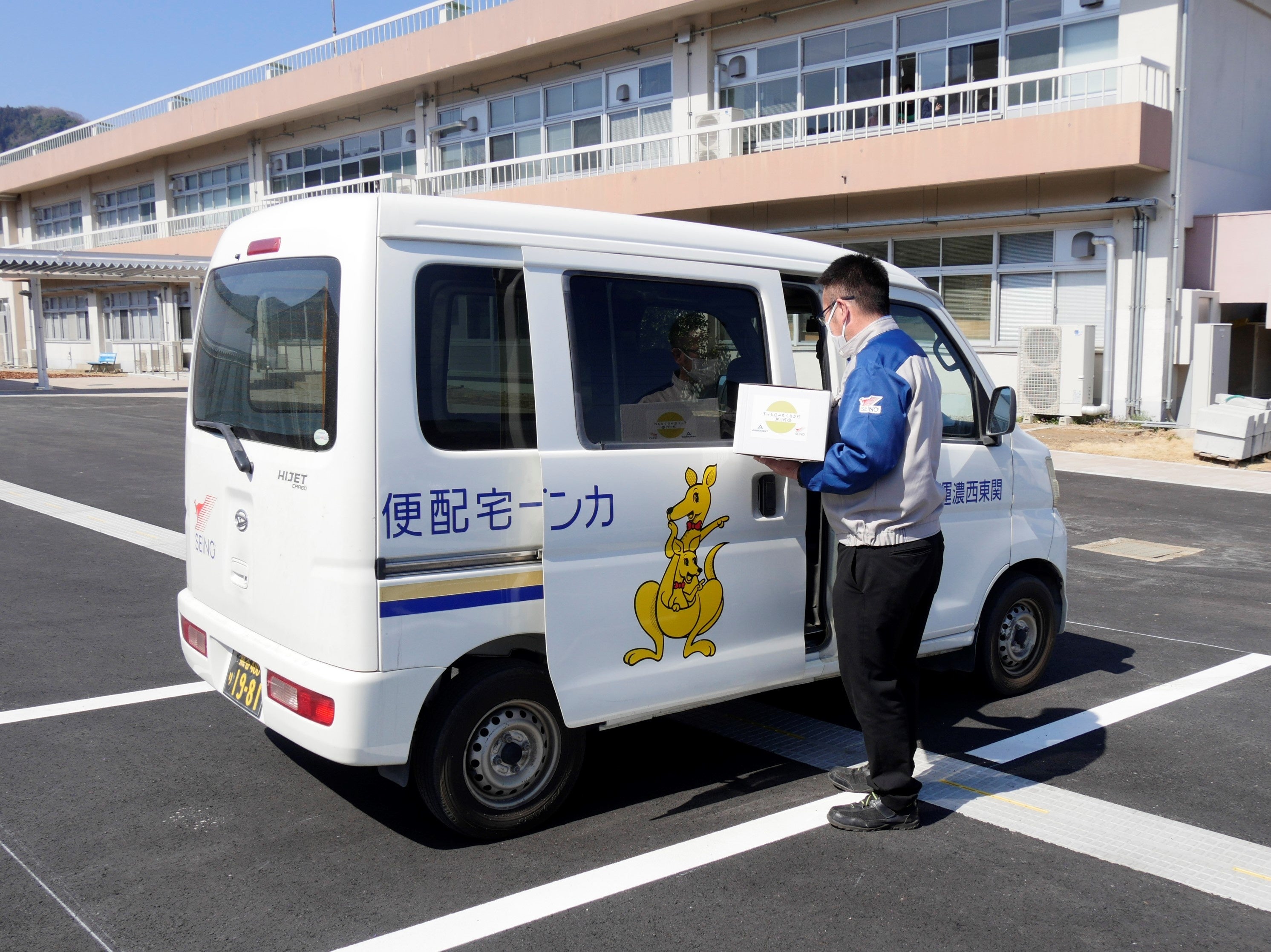 ドローン配送されたサイクリストのお土産の入った箱を車に積み替えリレー配送 （神川町多目的交流施設の駐車場）