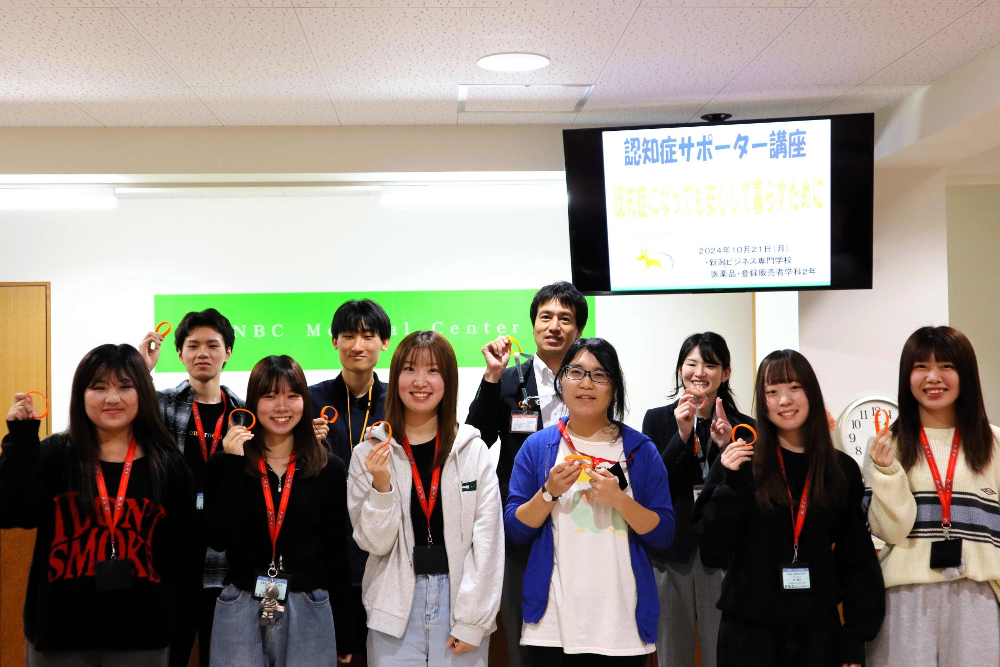 新潟ビジネス専門学校の学生が認知症サポーターの証「オレンジリング」を手に記念撮影している様子