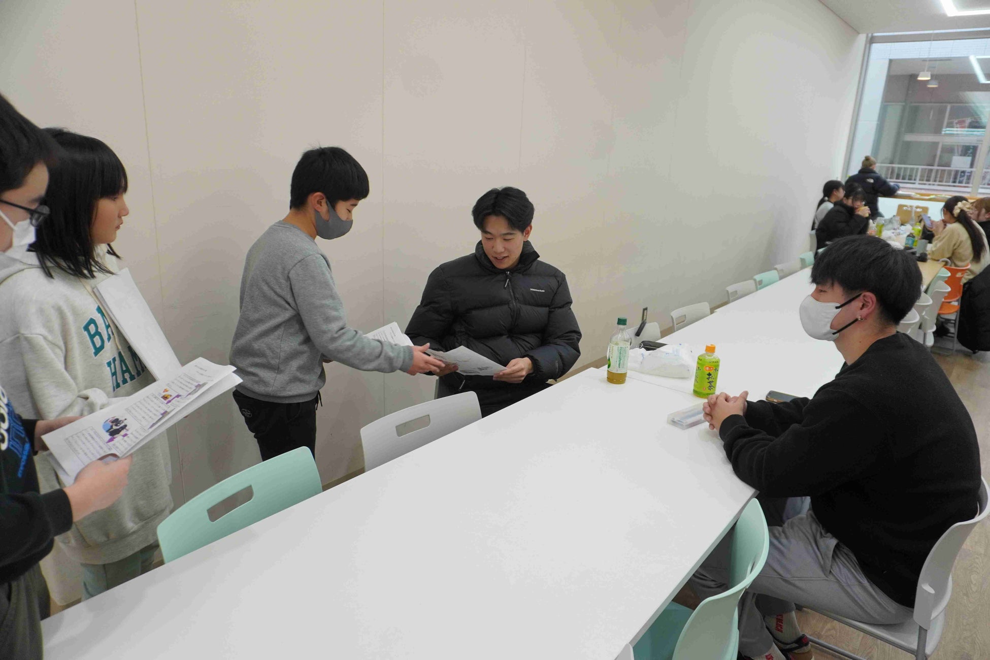 南浜小学校の5・6年生が学習成果の記された書面を新潟医療福祉大学の学生に手渡している様子