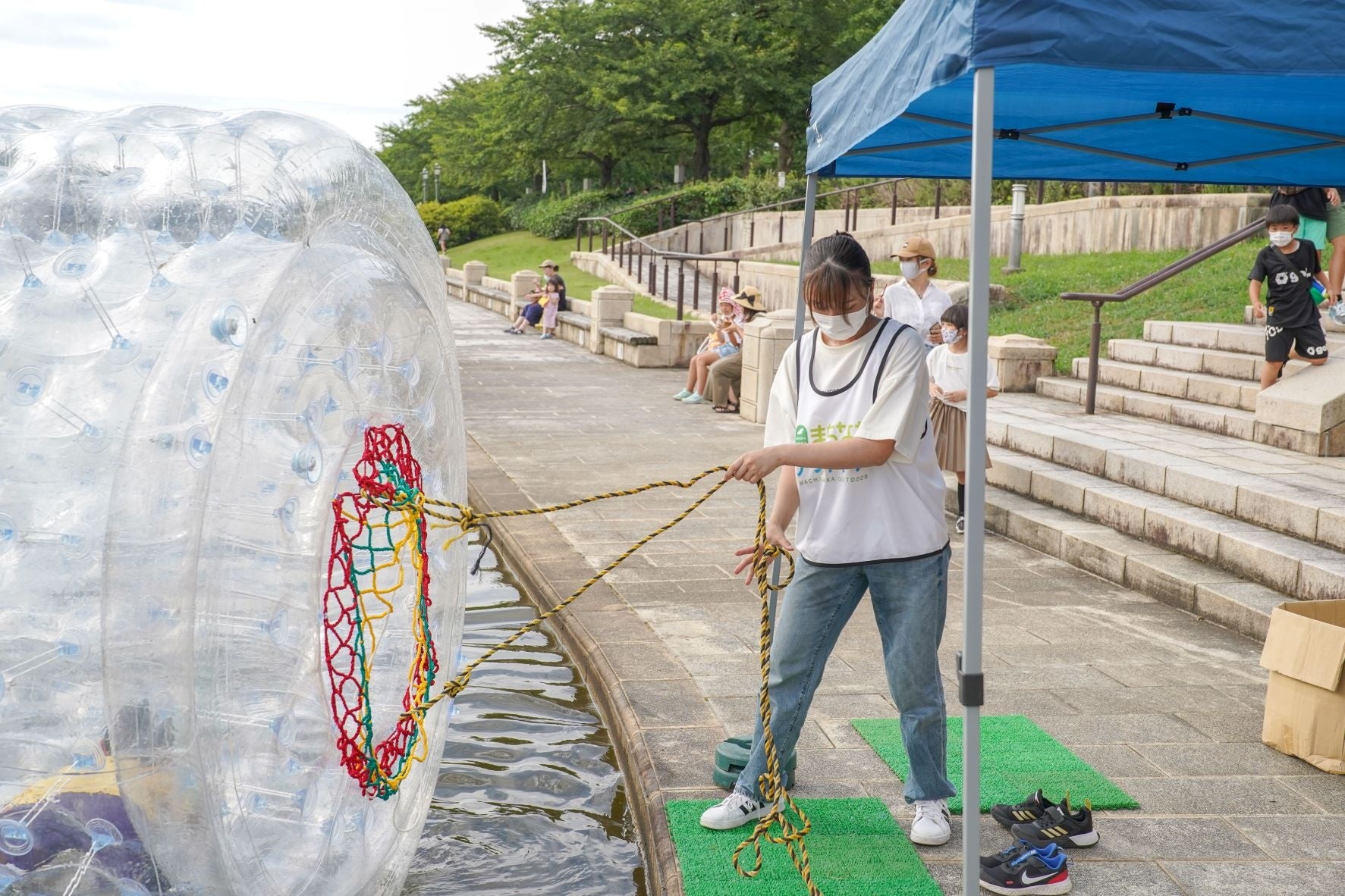 アクアチューブやトランポリンで遊ぶ子供たちを見守る学生