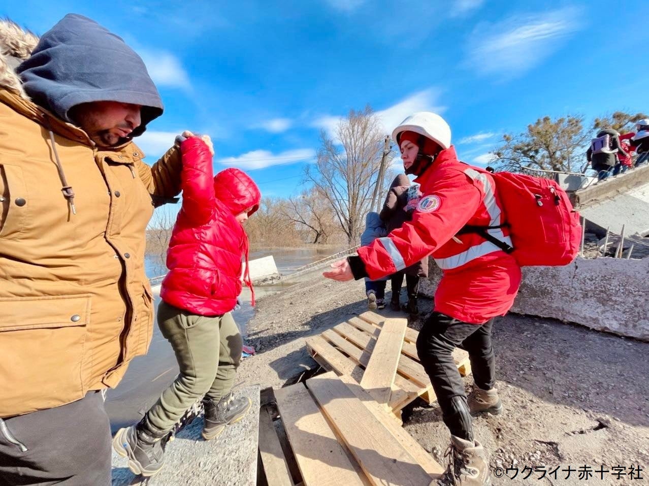 赤十字ボランティアが地元民とともに爆撃にあった橋を再建し、数千人の避難を誘導