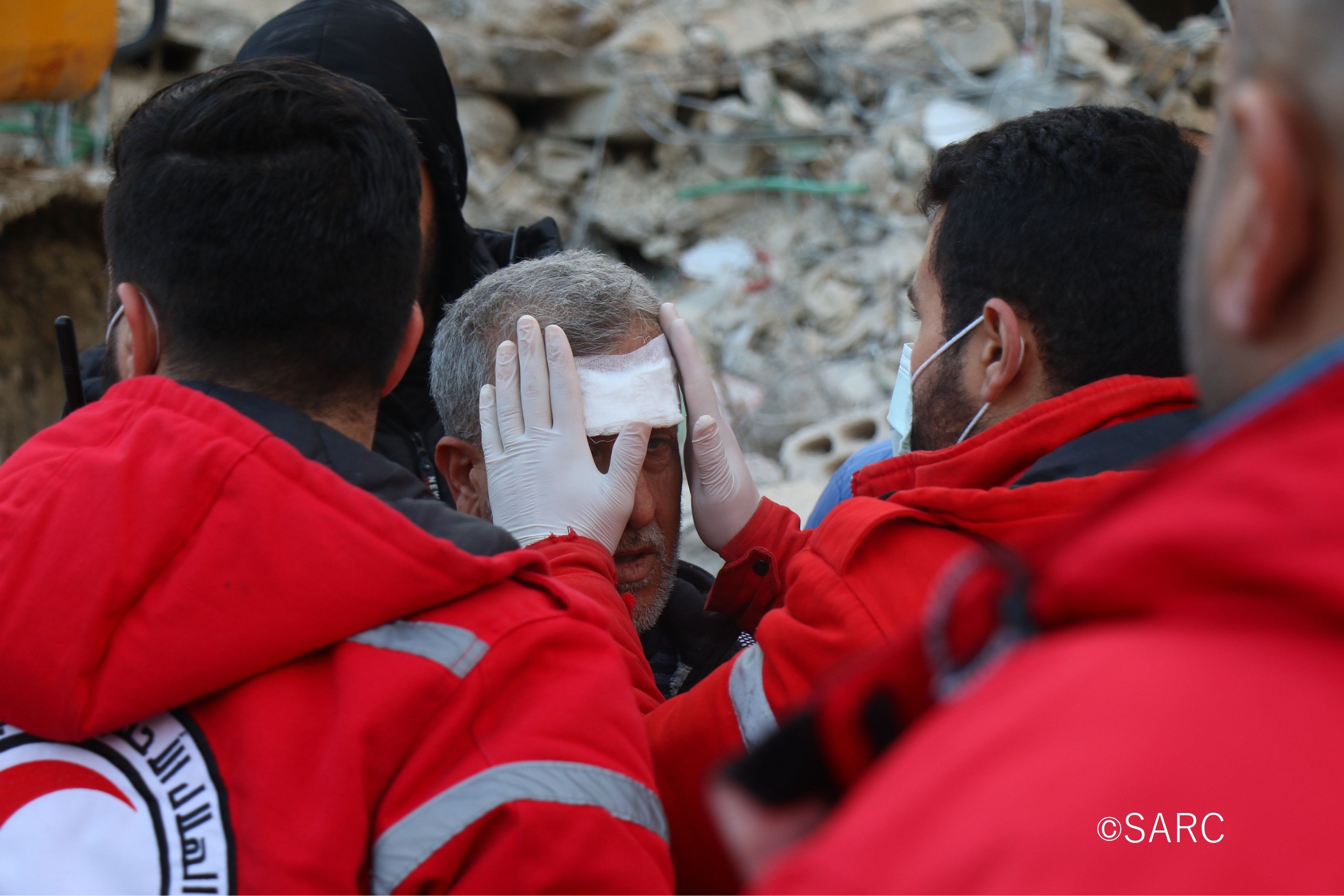 がれきの中から救出された負傷者の応急手当を施すシリア赤新月社のボランティア