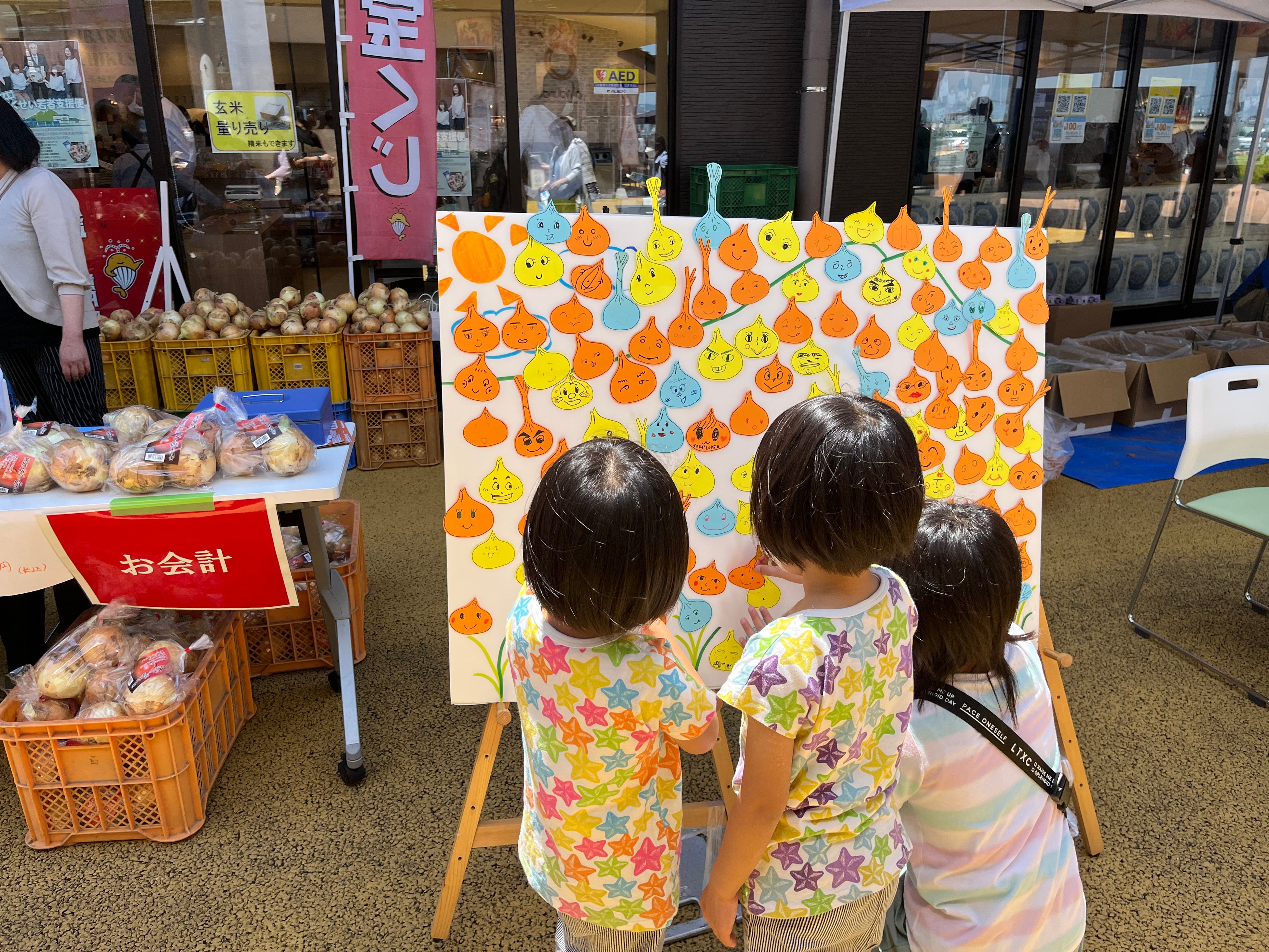 玉ねぎの形に切った色紙に顔を書いてもらい、ボードに張り付ける体験イベント