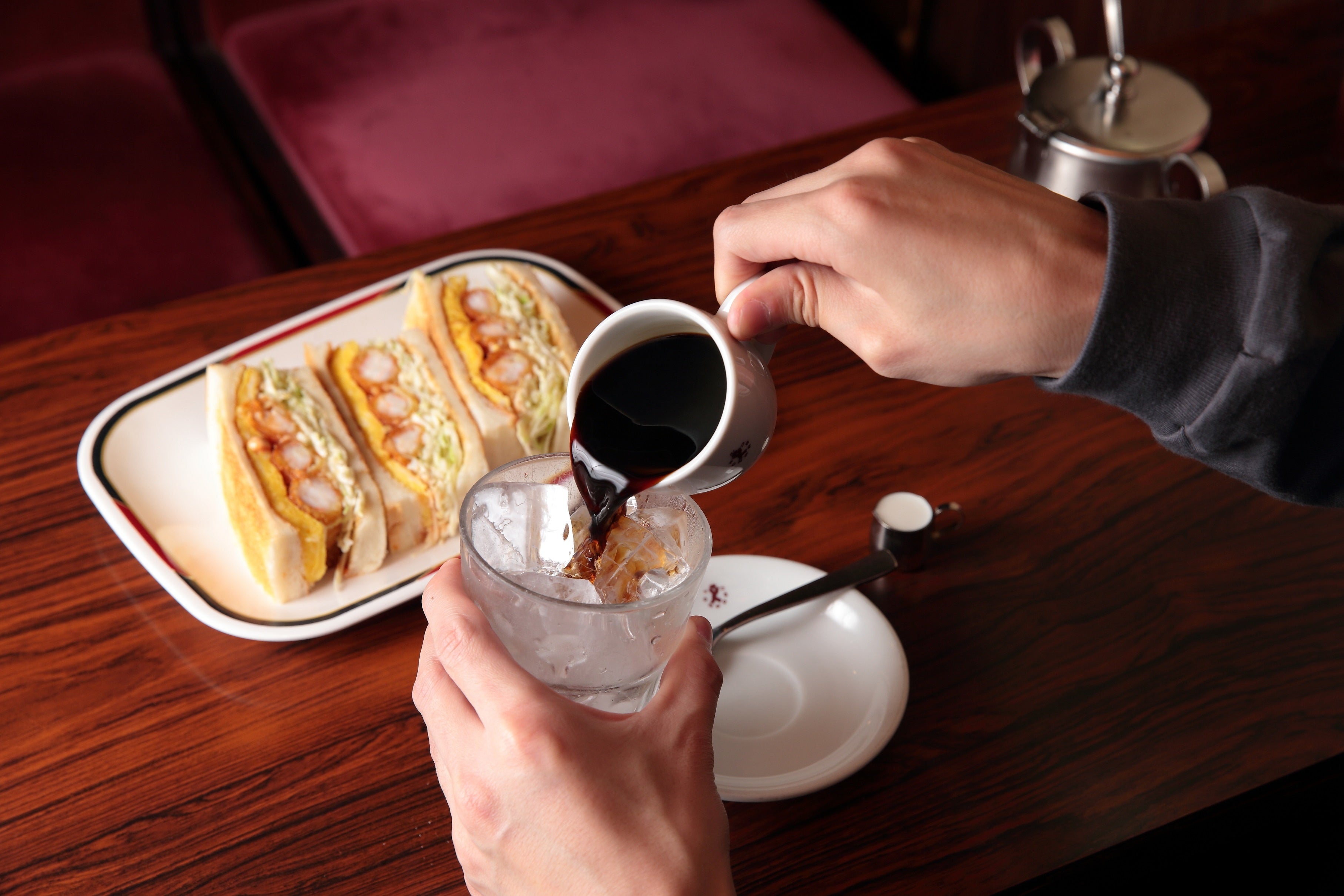 【手前】アイスコーヒーは熱いコーヒーに砂糖を溶かしてから氷の上に注ぐ。 【奥】オーダーが入ってから手作りだという。エビフライサンド。