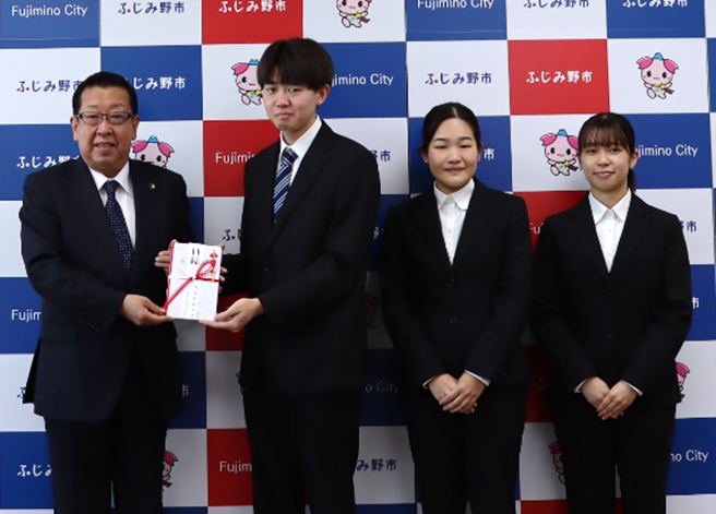 ふじみ野市高畑市長（写真左）に手渡しをするマッスルプロジェクト代表学生３名