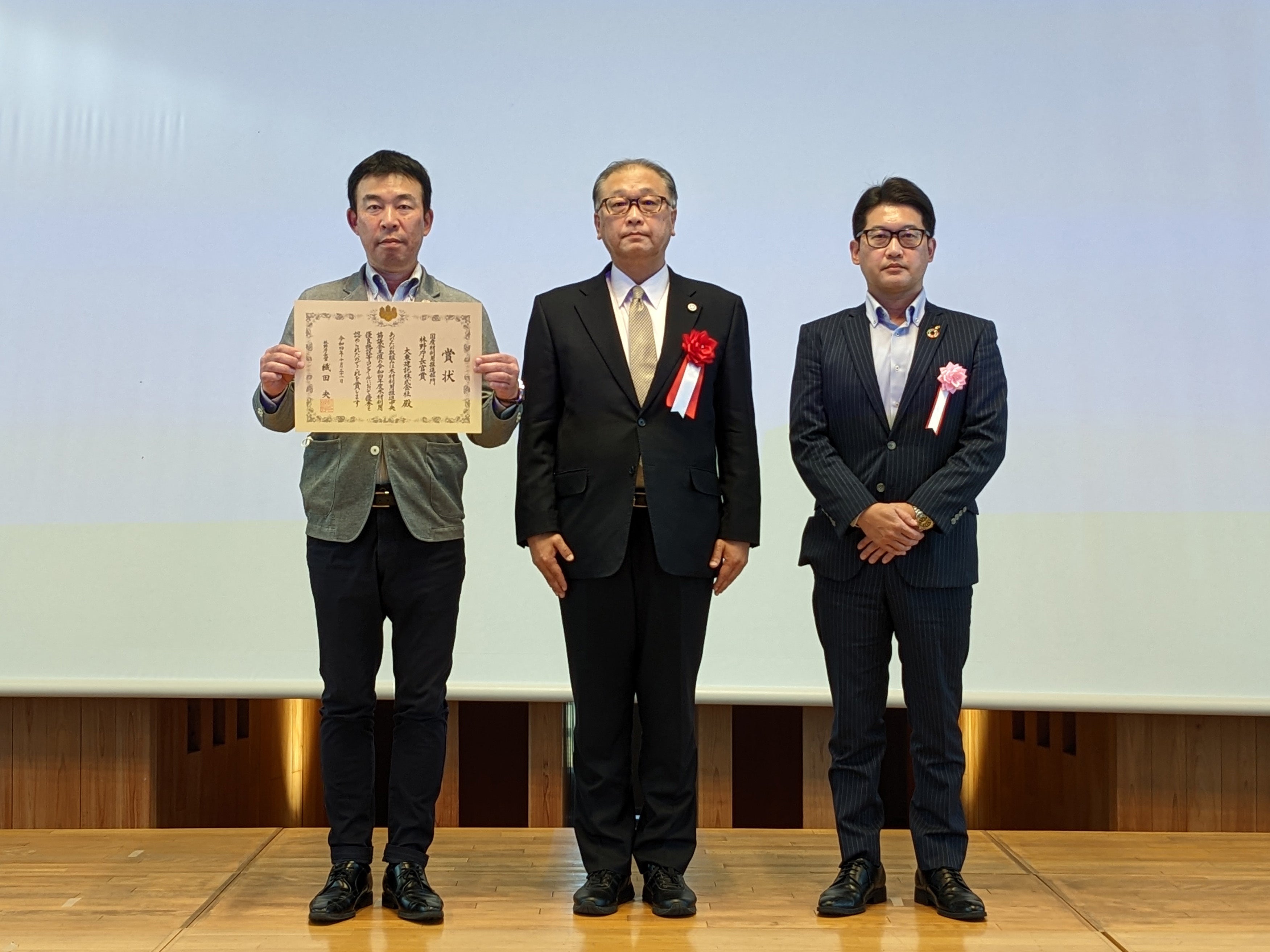 １０月３１日開催 令和４年度木材利用優良施設等コンクール表彰式 （左：大東建託（株） 取締役 舘 正文、中：林野庁長官　織田 央 氏、 右：大東建託（株） 技術開発部 次長 岡本 修司） 