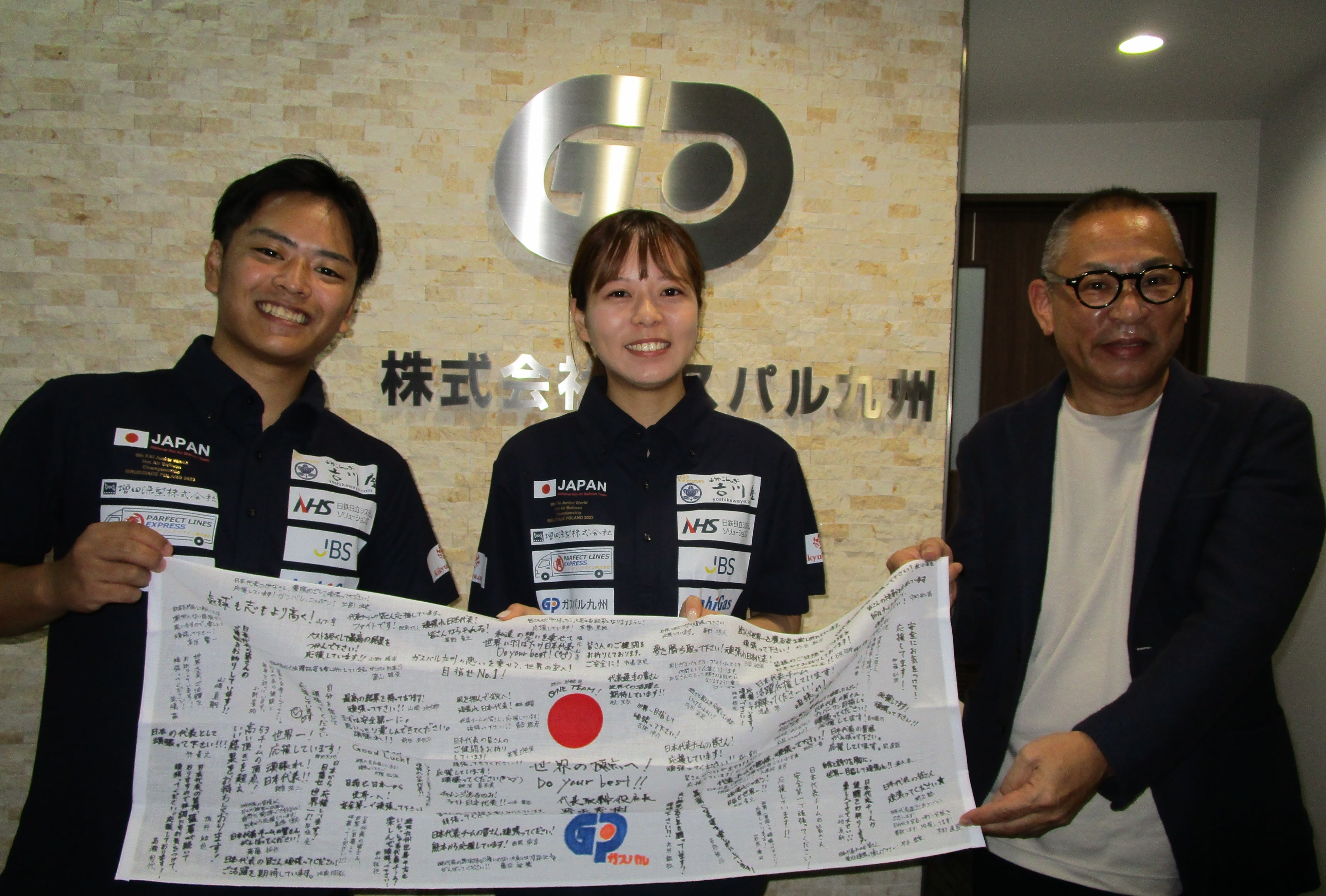 応援メッセージ入り手ぬぐいとともに左から、日本代表大坪さん、田中さん、ガスパル九州社長野坂