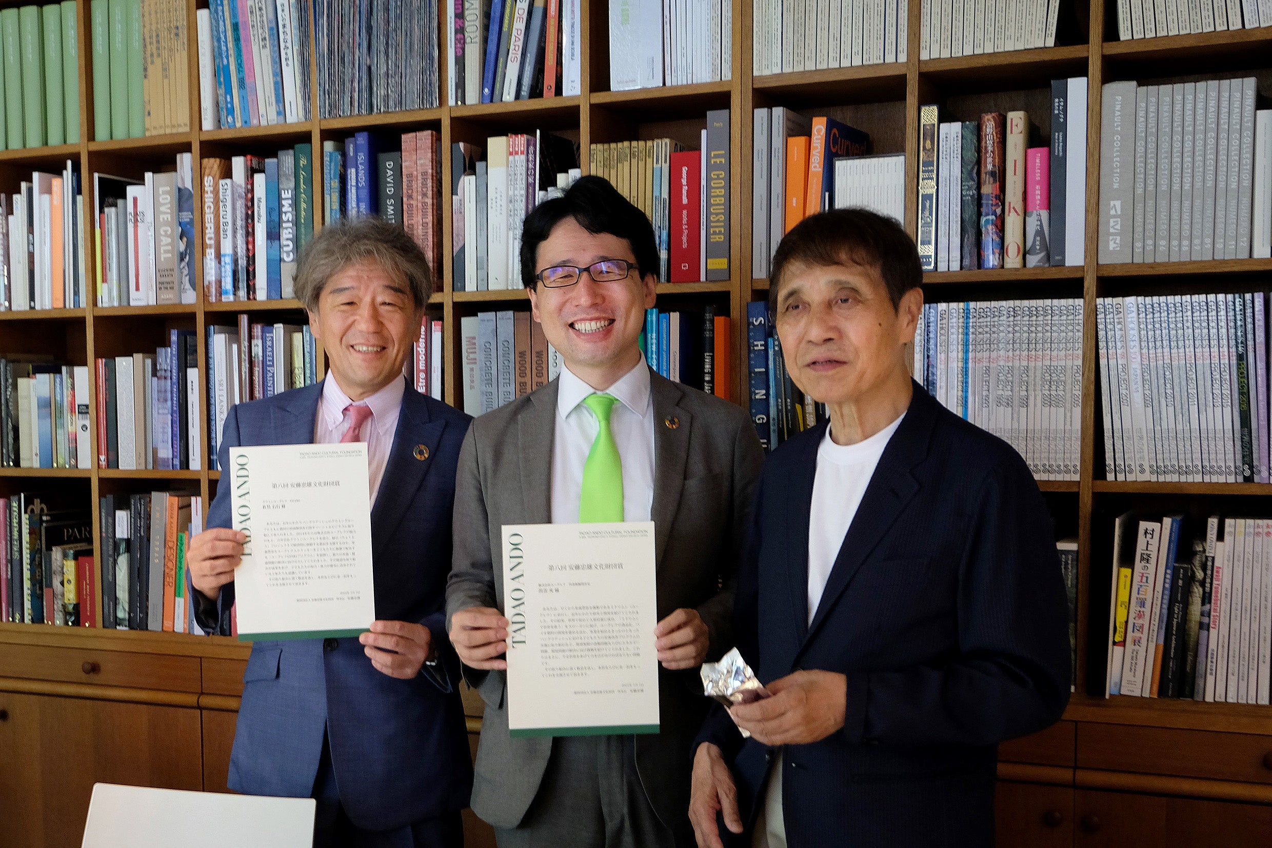 2022年7月7日　表彰式の様子　左から、ユーグレナ社代表取締役社長 出雲、グラミンユーグレナ社 Co-CEO 佐竹、安藤忠雄氏　安藤氏が手に持っているのは、「ユーグレナGENKIプログラム」で配布しているユーグレナクッキー