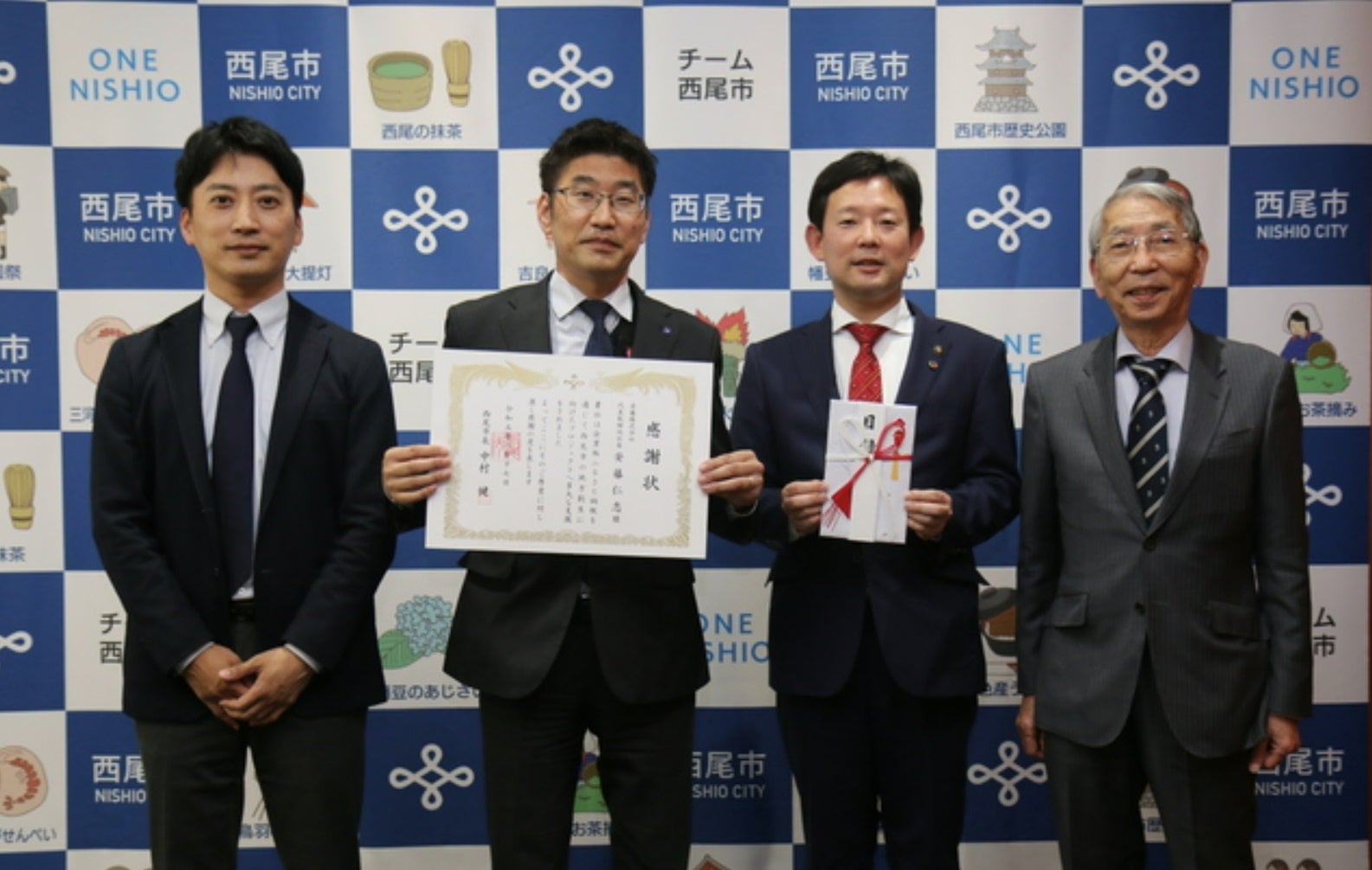 2023年1月17日、西尾市役所にて実施した企業版ふるさと納税寄附金贈呈式。中村健市長（右から2番目）と感謝状を掲げる安藤代表取締役社長（左から2番目）