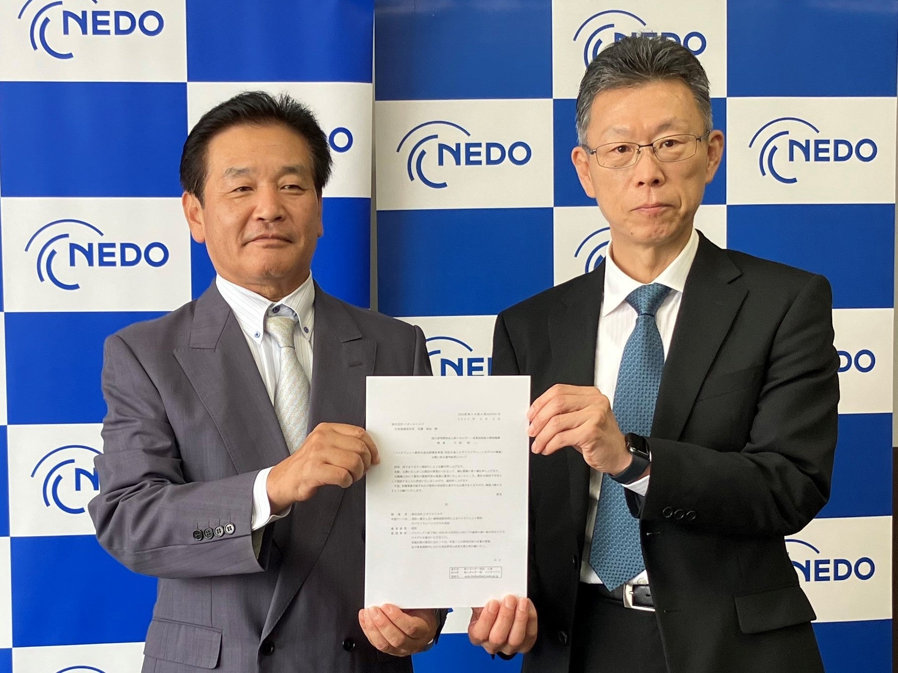 NEDOの弓取 修二 理事（右）と採択通知書を受領した 当社 取締役 常務執行役員CTO松本 英三（左）
