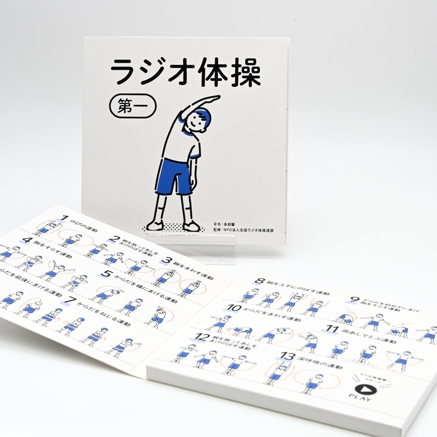 表紙（奥）と見開き（手前）。ラジオ体操の動きを見開きの図解で確認できます。