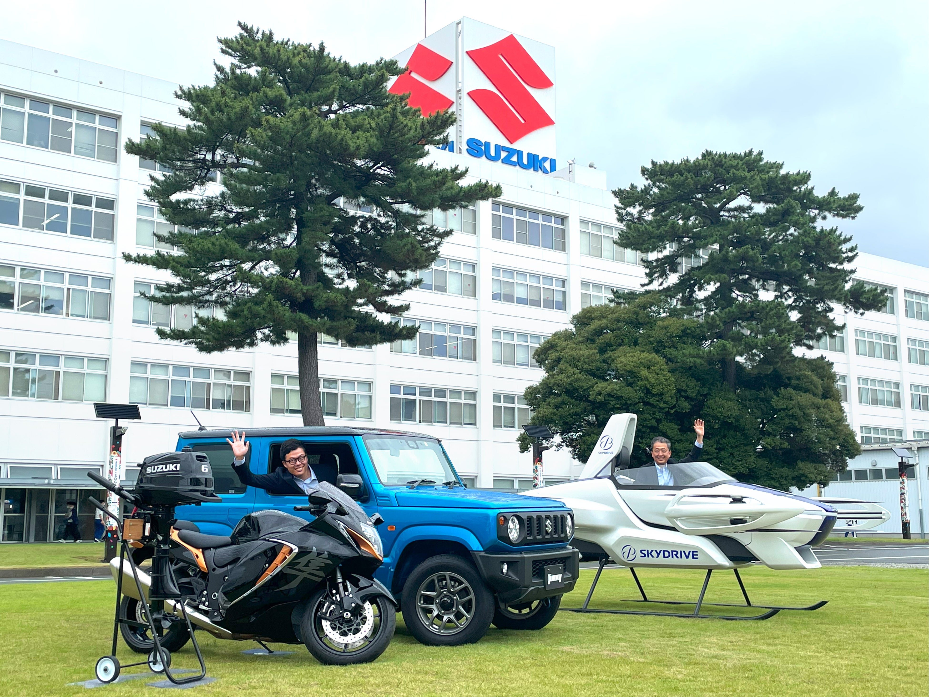 調印式の様子2　左からスズキの船外機、隼（Hayabusa）、ジムニー、SkyDriveのSD-03スケールモデル ジムニーにSkyDrive代表取締役の福澤 知浩、SD-03にスズキ常務役員 神代 英俊（敬称略）