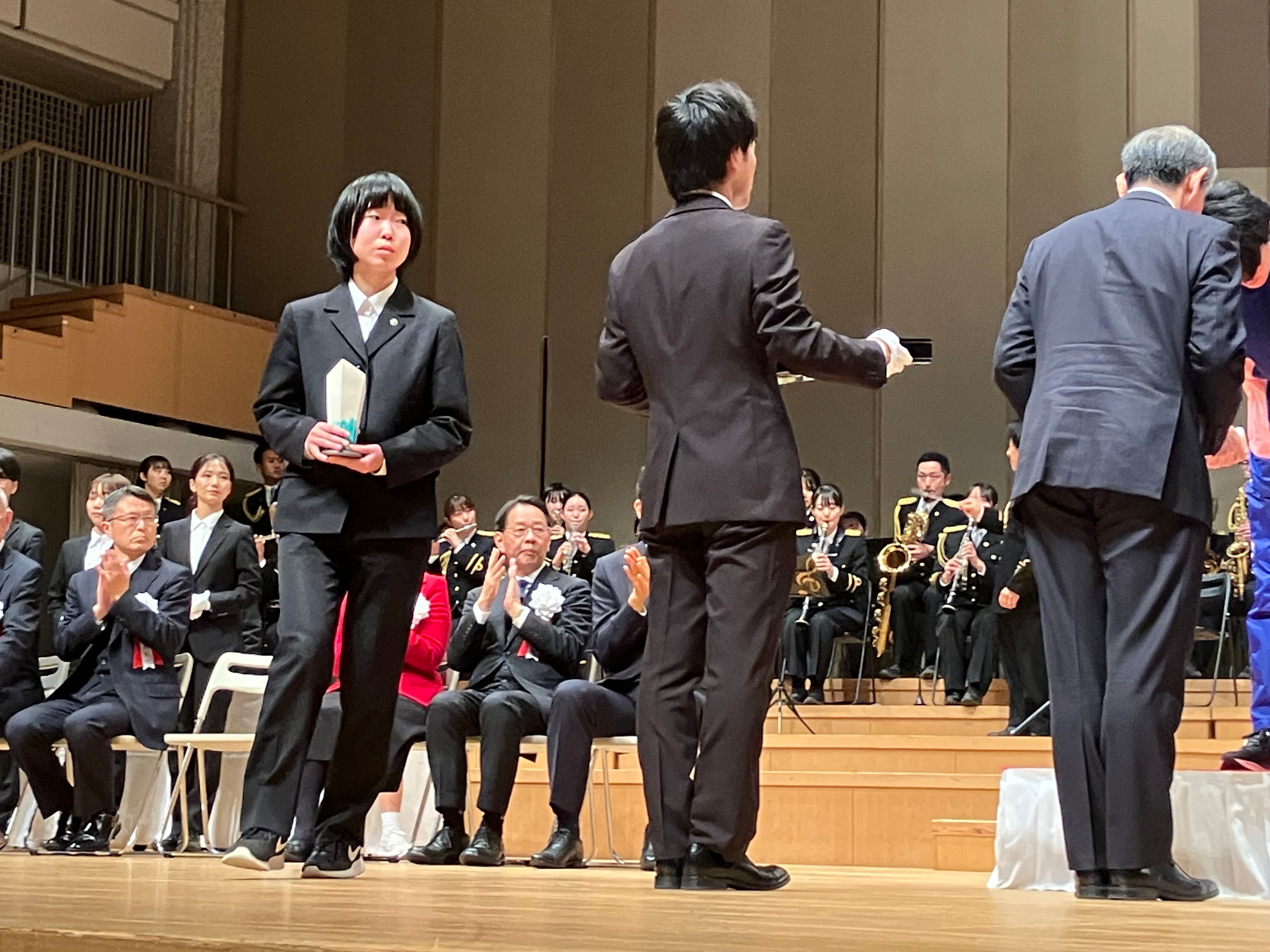 表彰式で、トロフィーを大切に運ぶ基町高等学校の生徒（左）