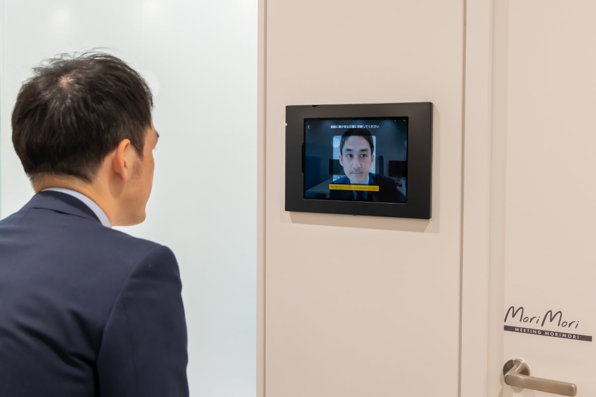 タブレット端末に顔をかざし、目の前の空室を予約する様子