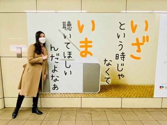 ABCラジオの広告と記念撮影する増田紗織アナウンサー