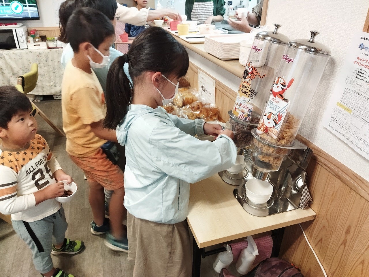 ディスペンサーからシリアルを入れる子ども