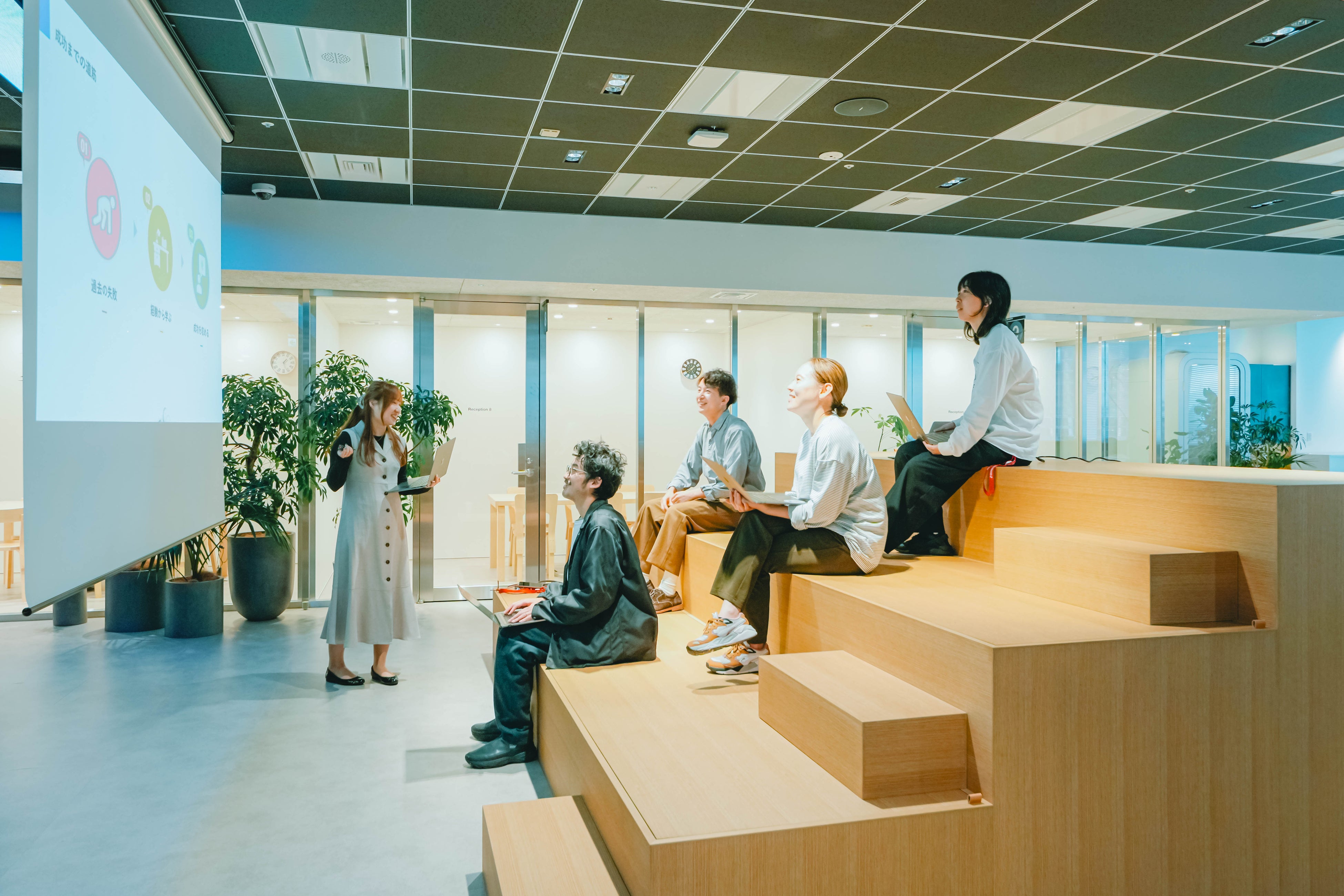 スクリーンとベンチを配置し、オープンスタイルで社内プレゼンテーションを行うスペースです。壁を作らずオープンな場で意見交換を行うことは、近くに座る他部署やグループ会社に刺激を与えます。