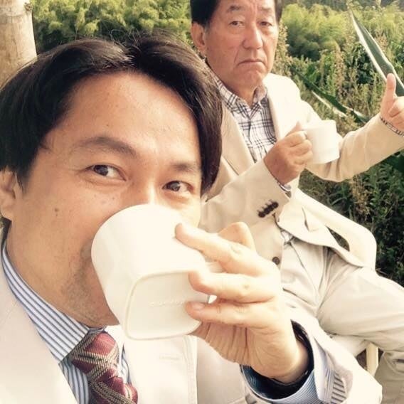 サザ農園でコーヒーを味わう会長鈴木誉志男（写真右）と、社長鈴木太郎（写真左）