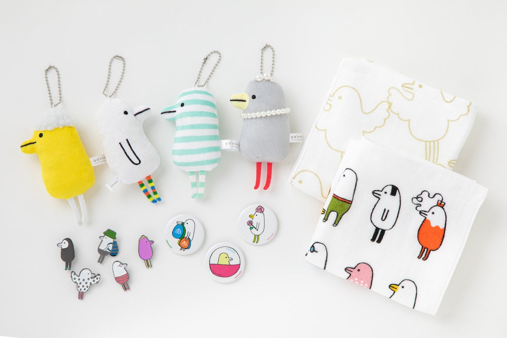 （販売予定のほぼトリドリのグッズ。上段左：キーホルダー、下段左より：ピンズ、缶バッジ、右：タオル）