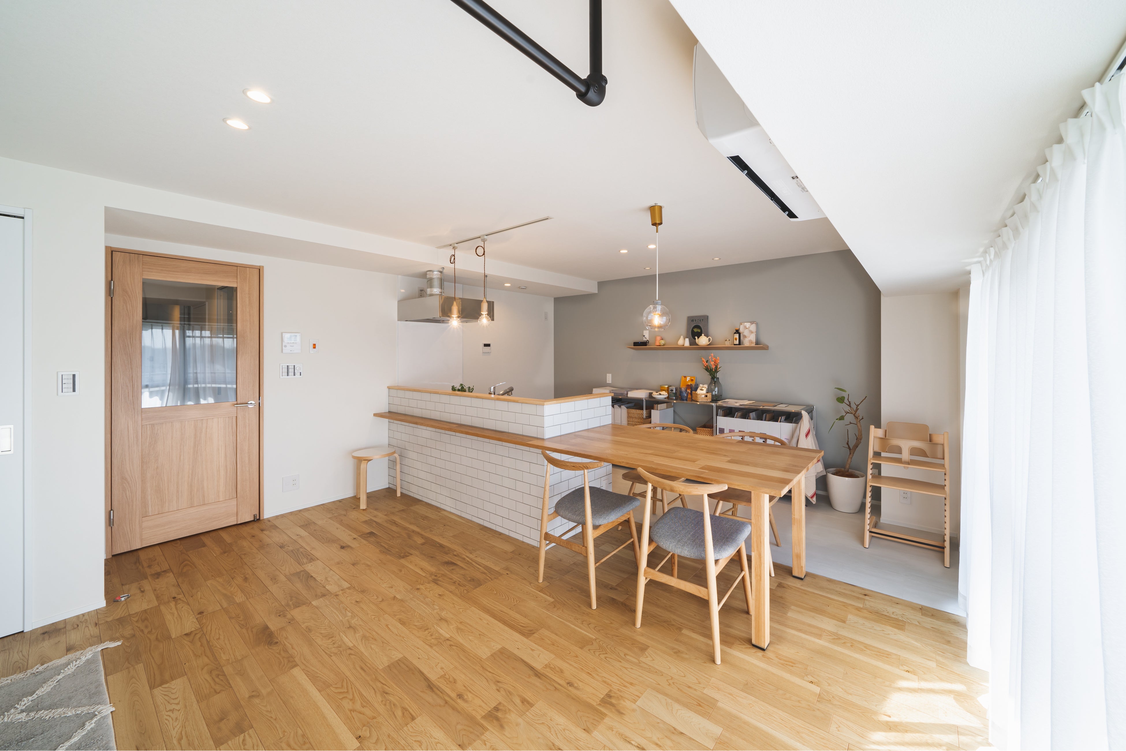 白いタイルの造作キッチンが目を引く。白とグレーと木目で優しい印象