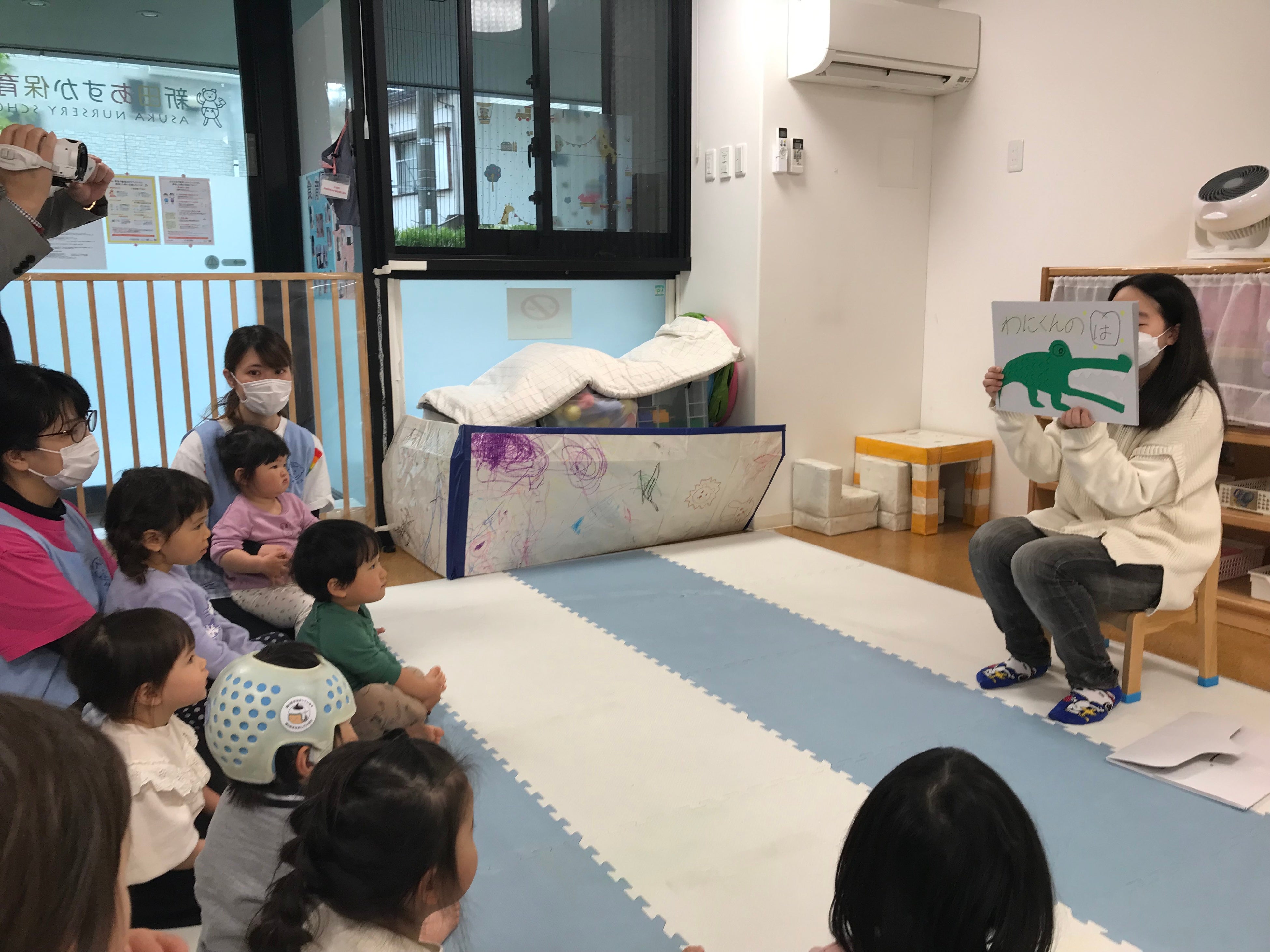 ＜手作り紙芝居を演じる保育学生と集中して参加する子どもたちの様子＞