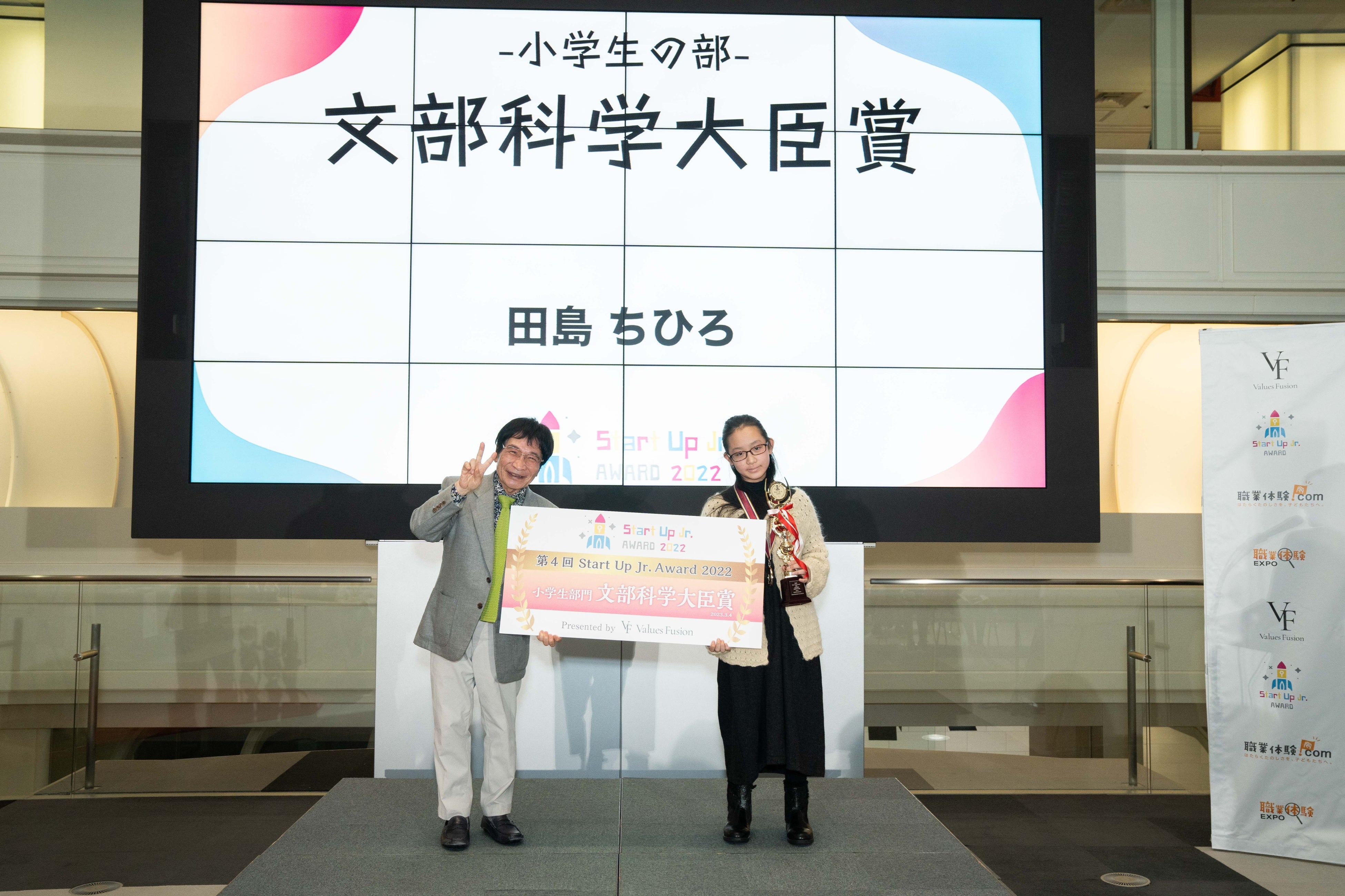 審査員の尾木直樹氏よりトロフィーとパネルを授与される田島ちひろさん