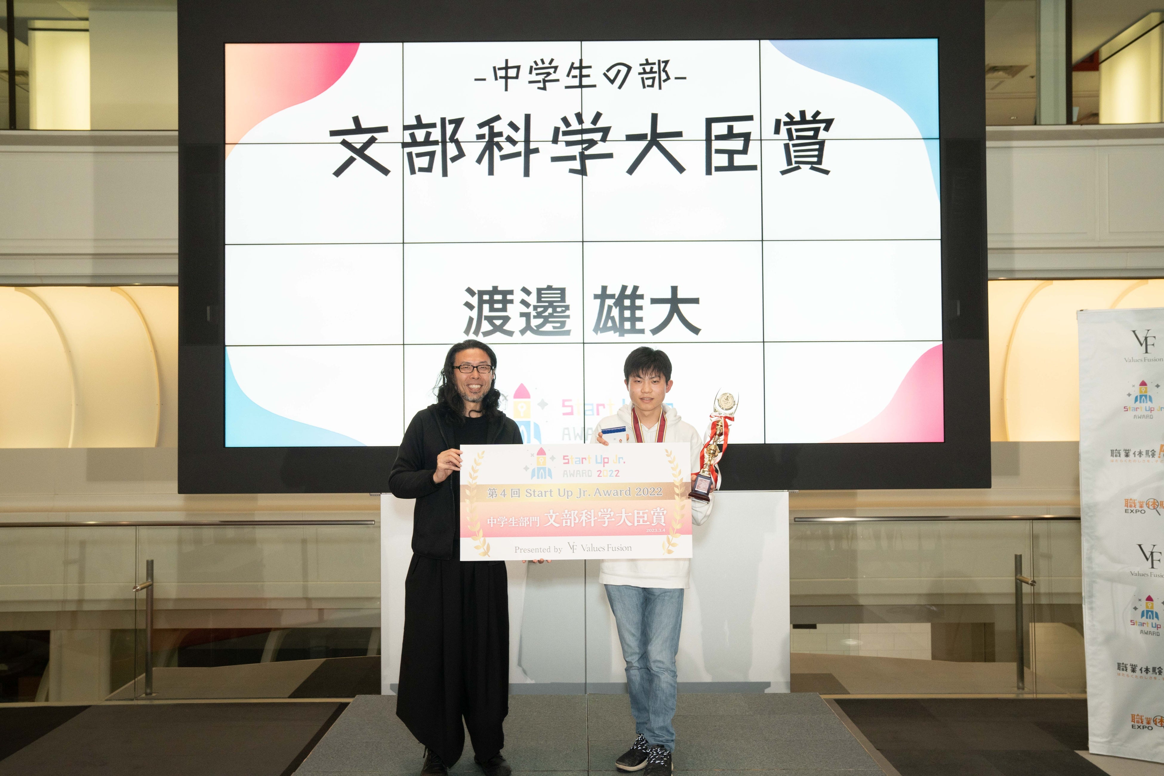 審査員長の（一社）プレゼンテーション協会代表理事 前田鎌利氏よりトロフィーとパネルを授与される渡邉雄大さん