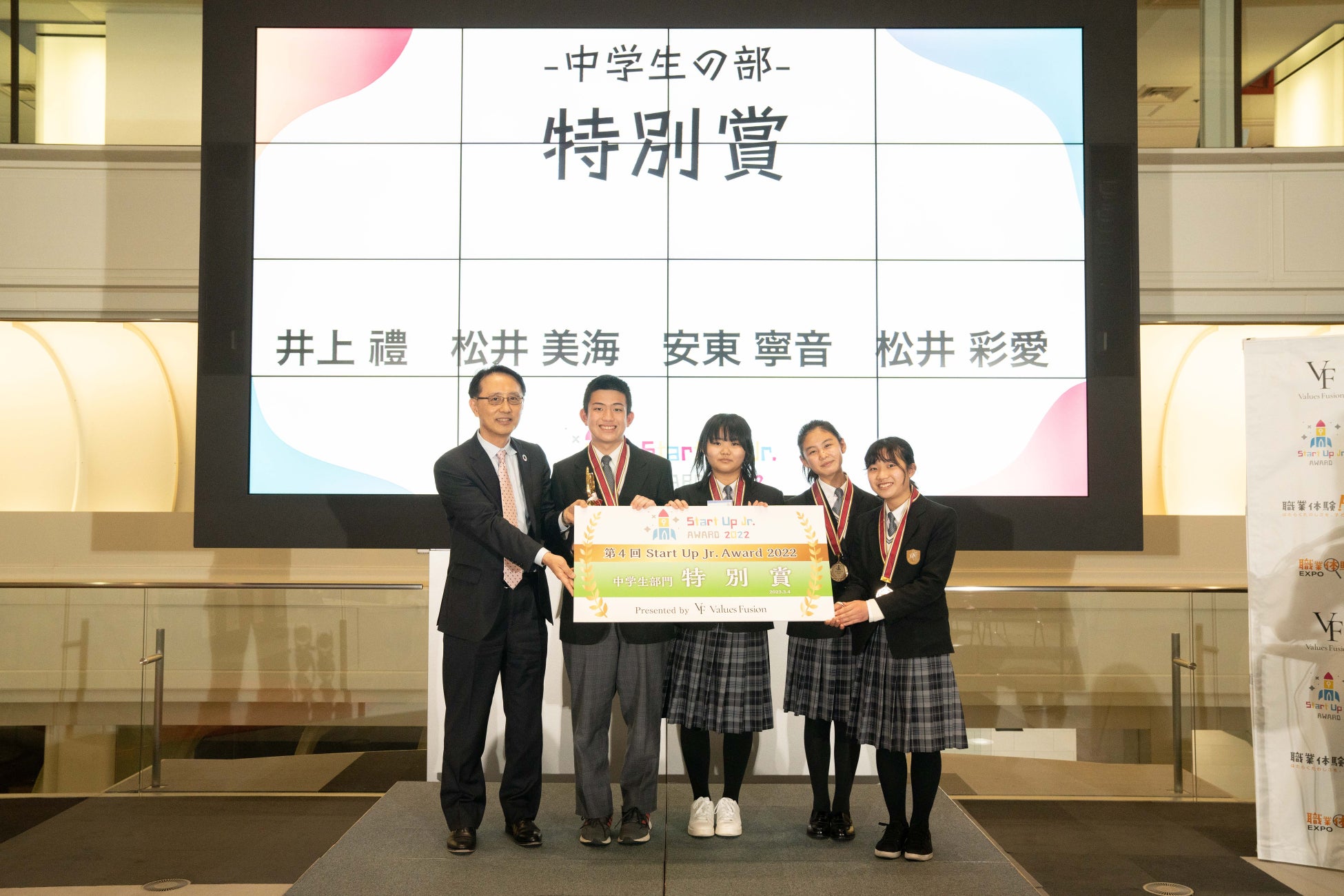 協賛の(株)東京証券取引所 長谷川高顕氏よりトロフィーとパネルを授与される井上禮さん、松井美海さん、安東寧音さん、松井彩愛さん