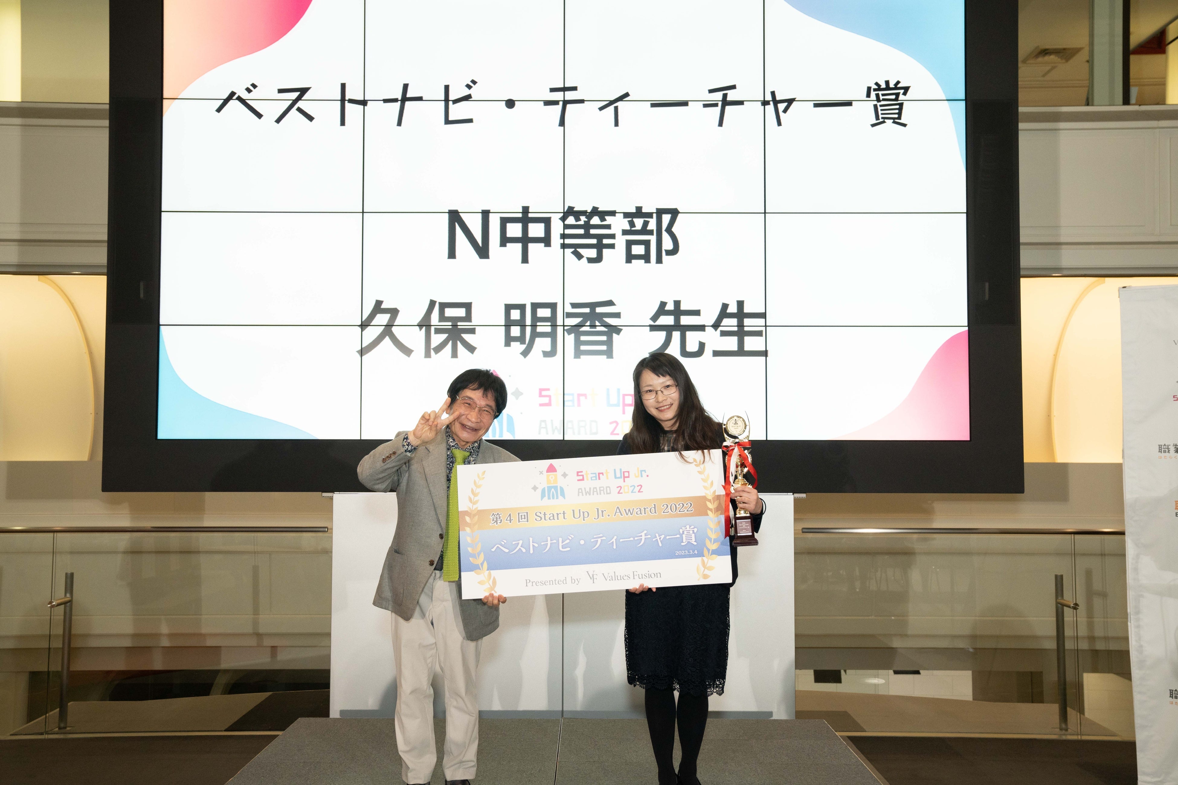 審査員の尾木直樹氏よりトロフィーとパネルを授与されるN中等部の久保明日香先生