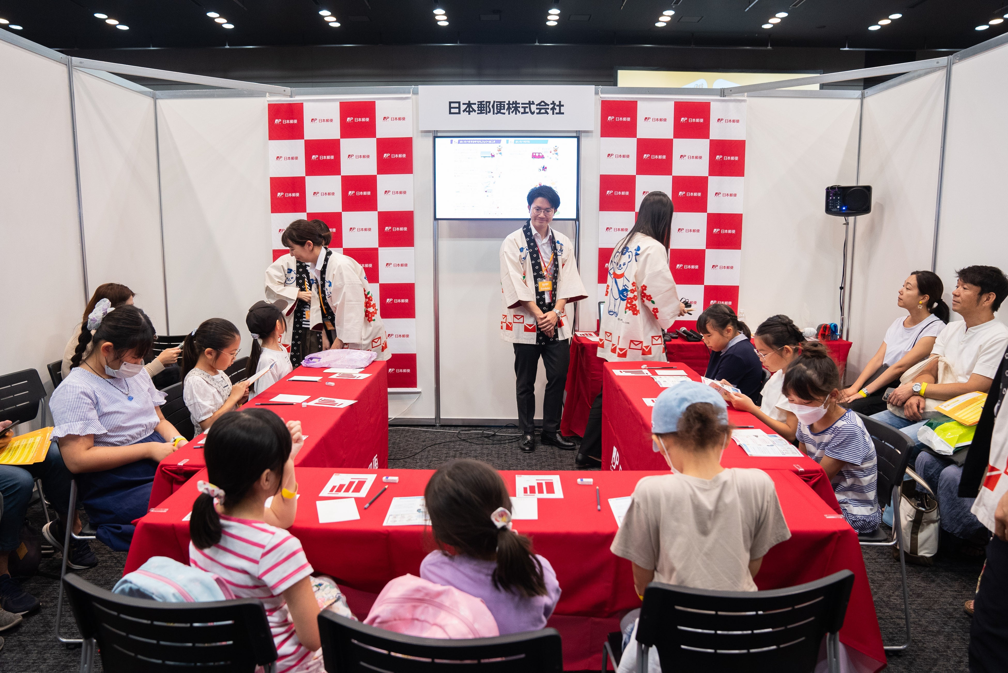 日本郵便のブースより。葉書に宛名を書く体験を通じて、手紙が届く仕組みを学ぶ子どもたち