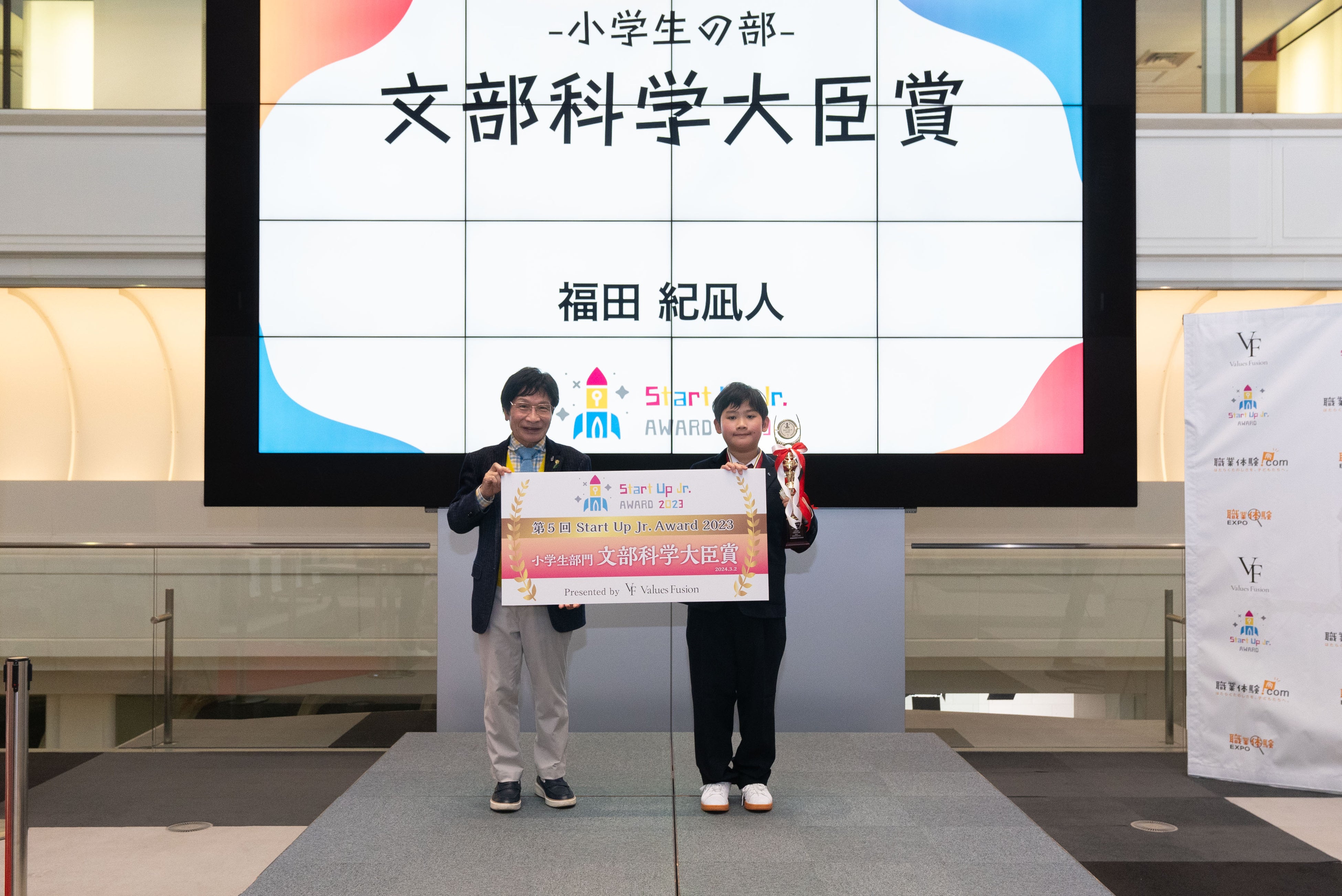 特別審査員の尾木直樹氏よりトロフィーとパネルを 授与される福田 紀凪人さん