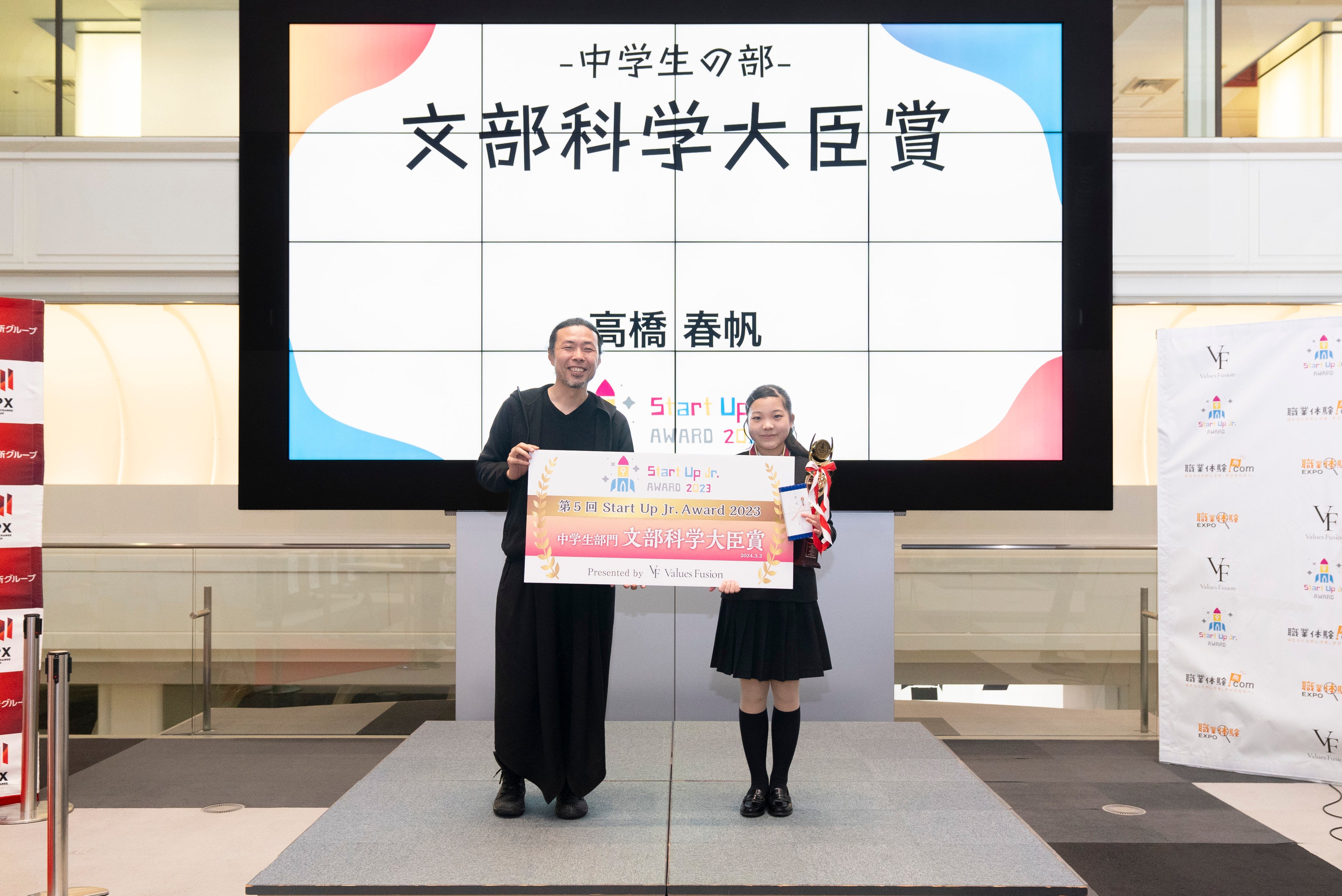 審査員長の（一社）プレゼンテーション協会代表理事&nbsp; 前田鎌利氏よりトロフィーとパネルを授与される髙橋 春帆さん