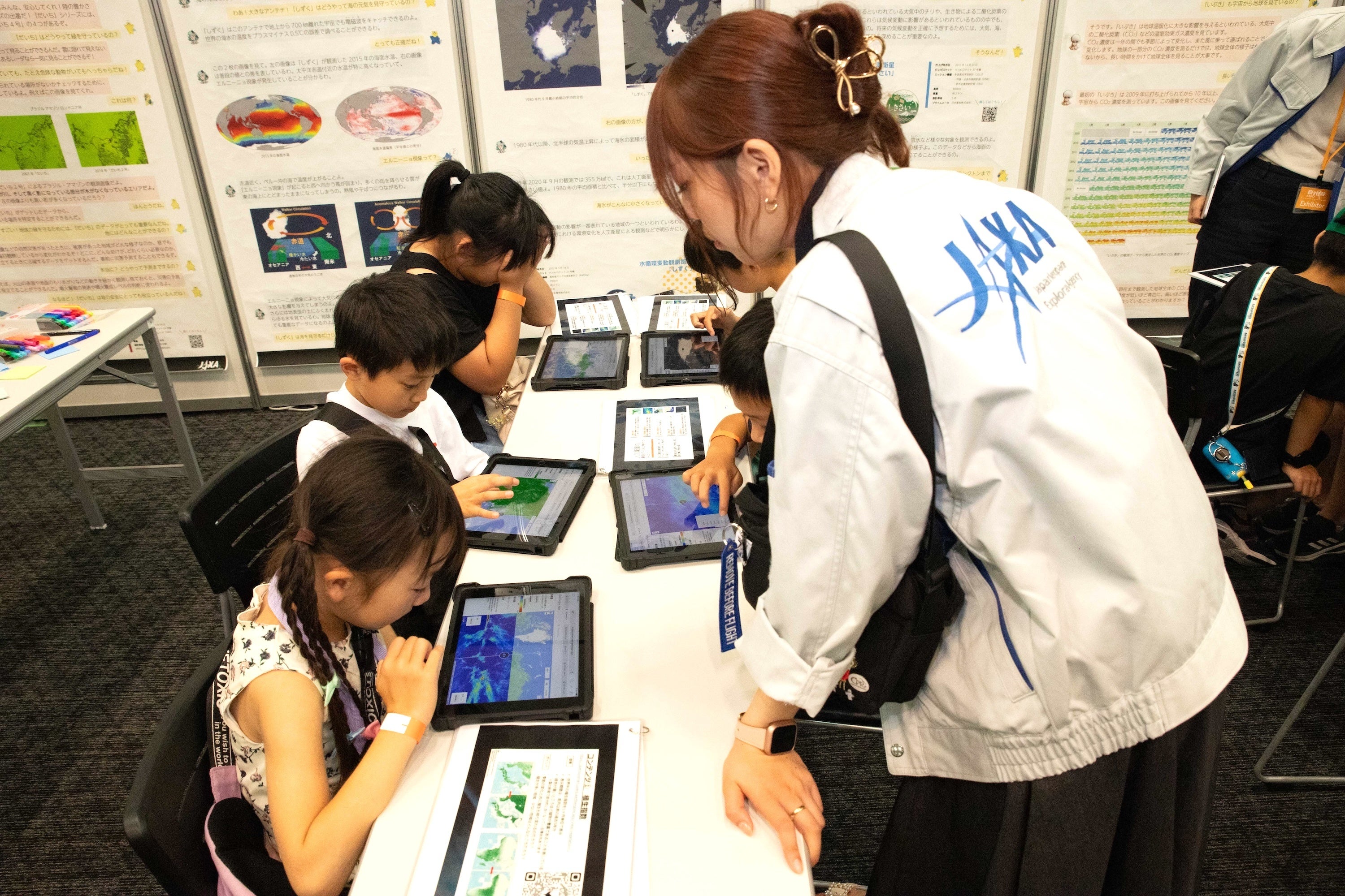 JAXAのブースより。地球観測衛星の観測データを使って、JAXAの仕事を学ぶ子どもたち
